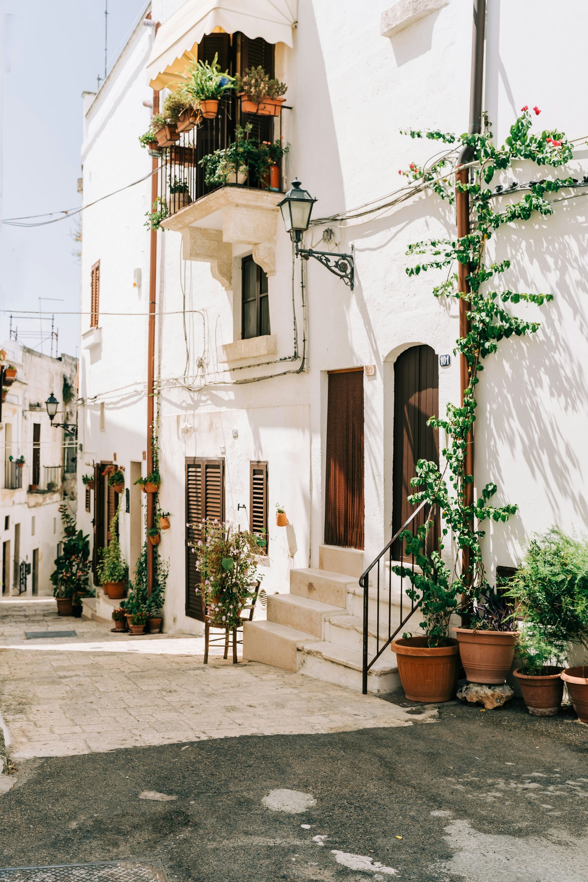 A white building with potted plants on the side of it in Puglia, Italy.