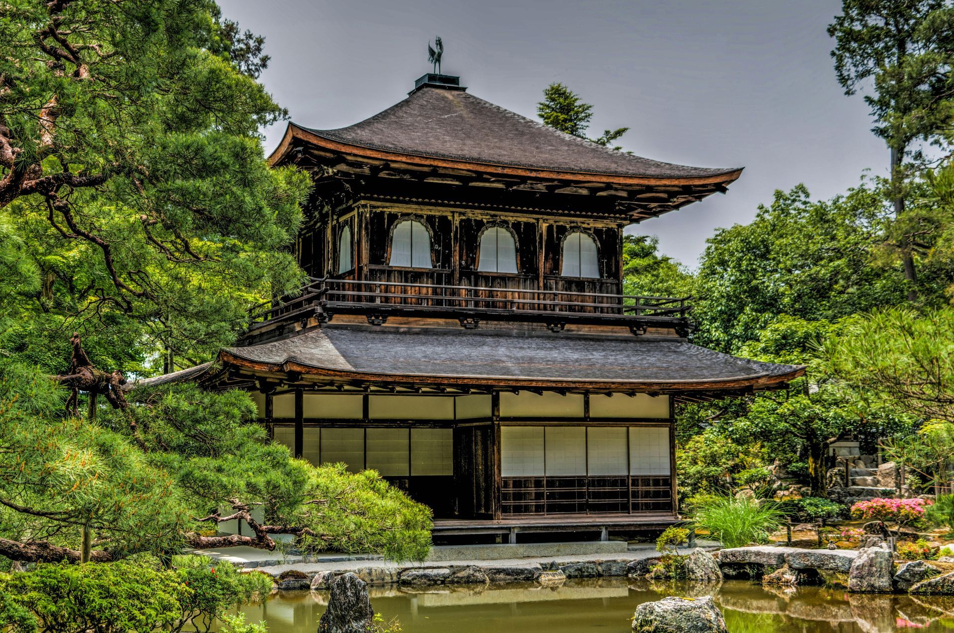 A temple with a pond in front of it surrounded by trees in Japan.