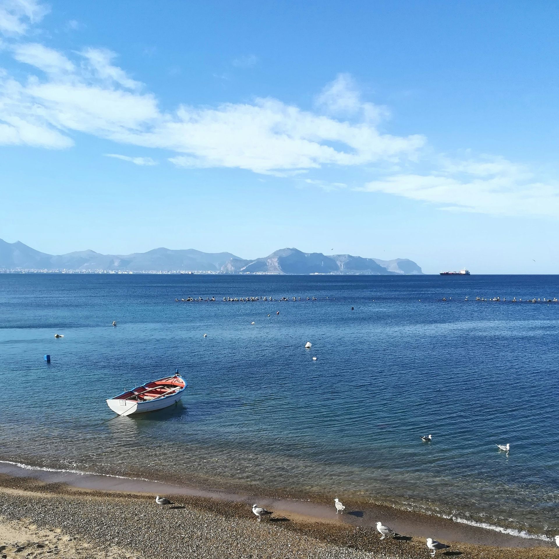 A boat is floating on the water near a beach in Sicily.