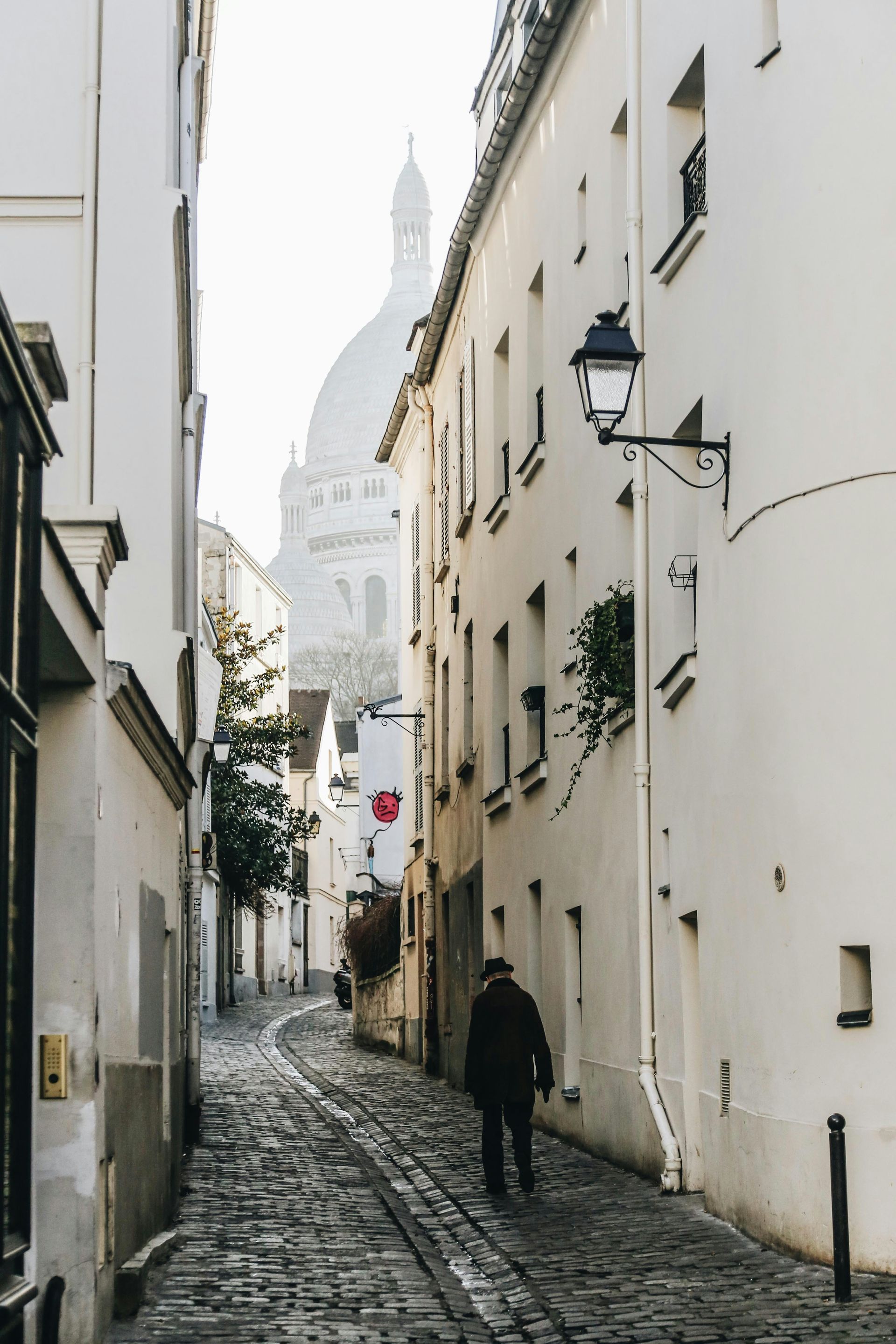 A cobblestone street with a view of Basilique du Sacré-Cœur de Montmartre in the background in Paris, France.