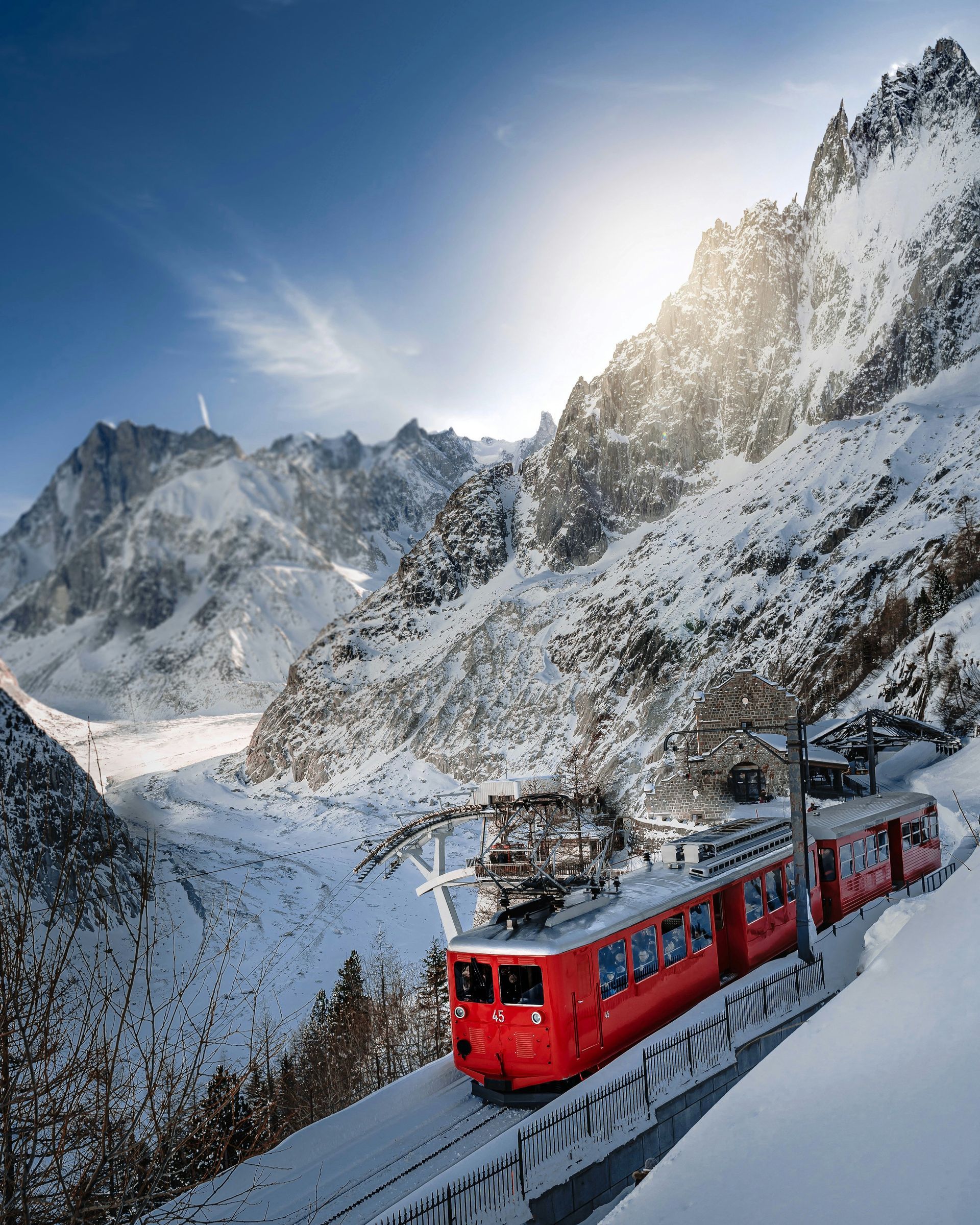 A red train is going down a snowy mountain in Chamonix, France.