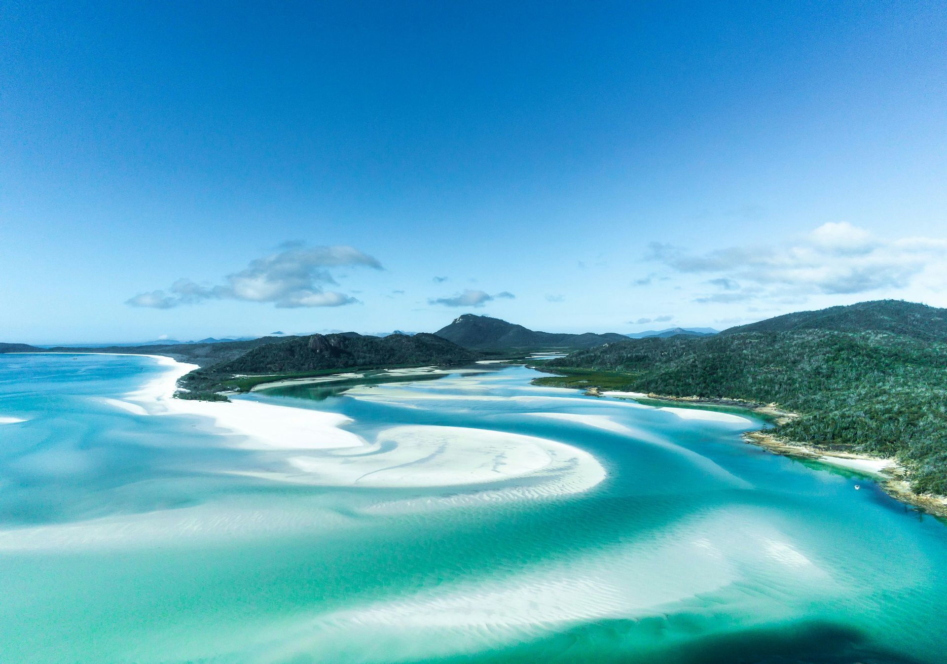 An aerial view of a large body of water with mountains in the background in the Whitsundays, Australia. 