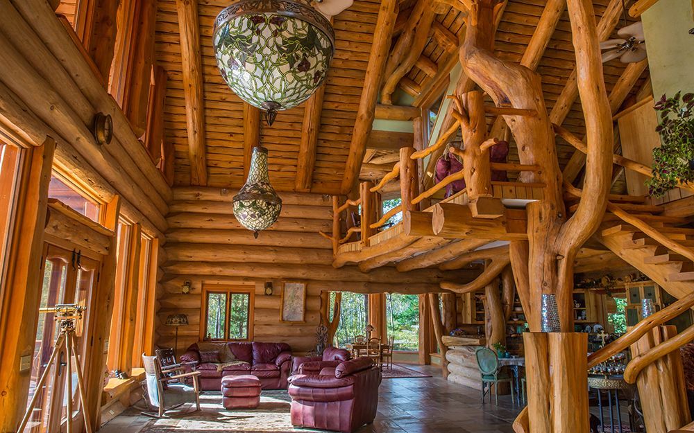 A large log cabin with a living room and stairs on Chilko Lake, Canada.