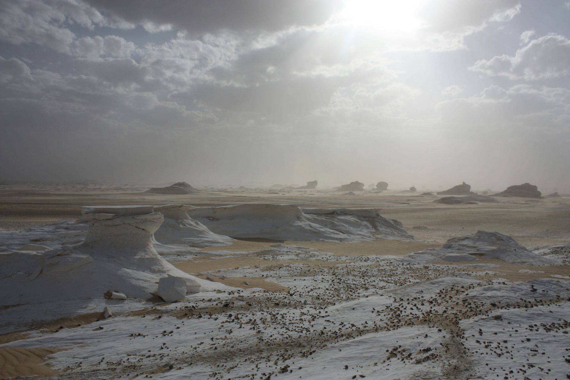 The sun is shining through the clouds over White Desert National Park in Egypt.