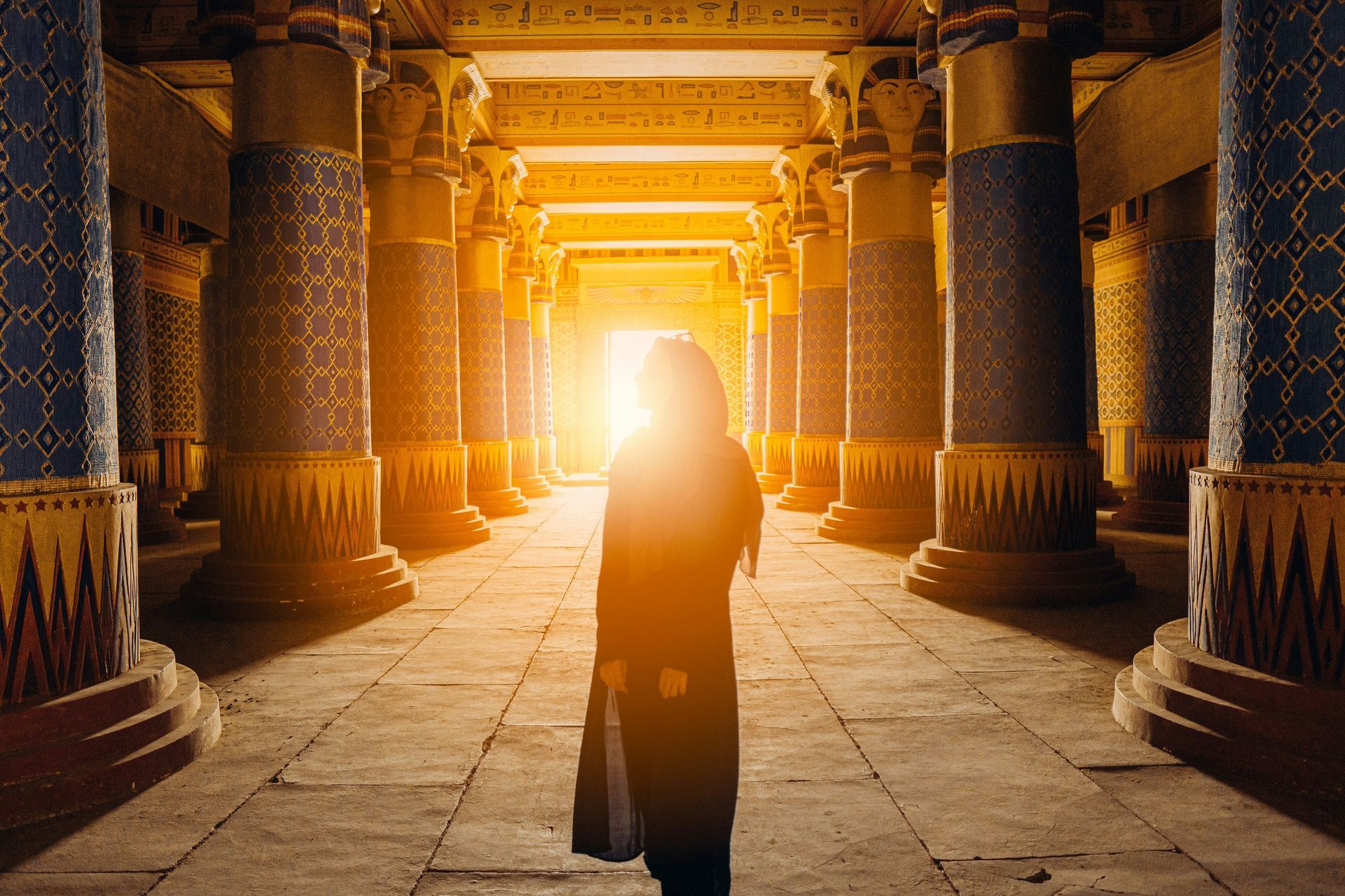 A woman is standing in an ancient building with columns and the sun is shining through the columns in Ouarzazate, Morocco.