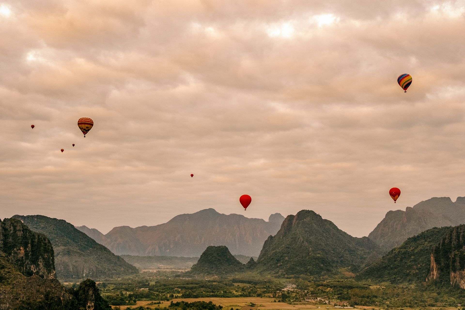 Hot air balloons over a valley with mountains in Vang Vieng, Laos.
