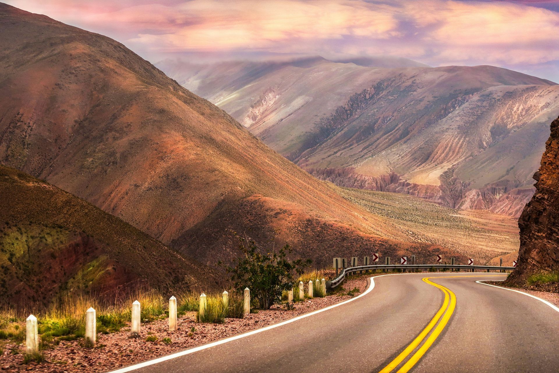 Winding road through mountains, bathed in sunlight; orange and purple hues in Salta, Argentina.