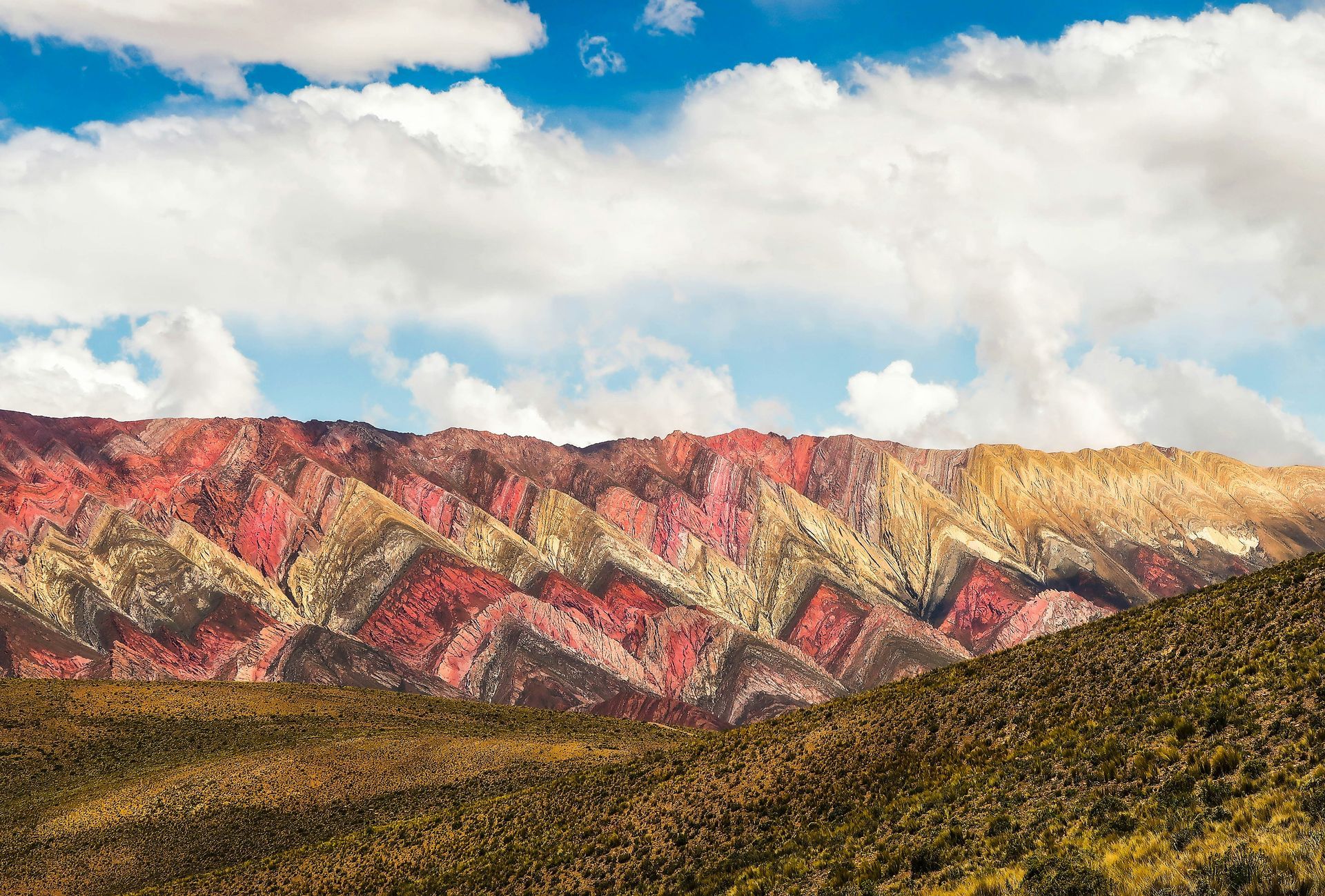 Rainbow mountains with red, pink, yellow, and brown stripes in the Cerro de los 14 Colores in Salta, Argentina.