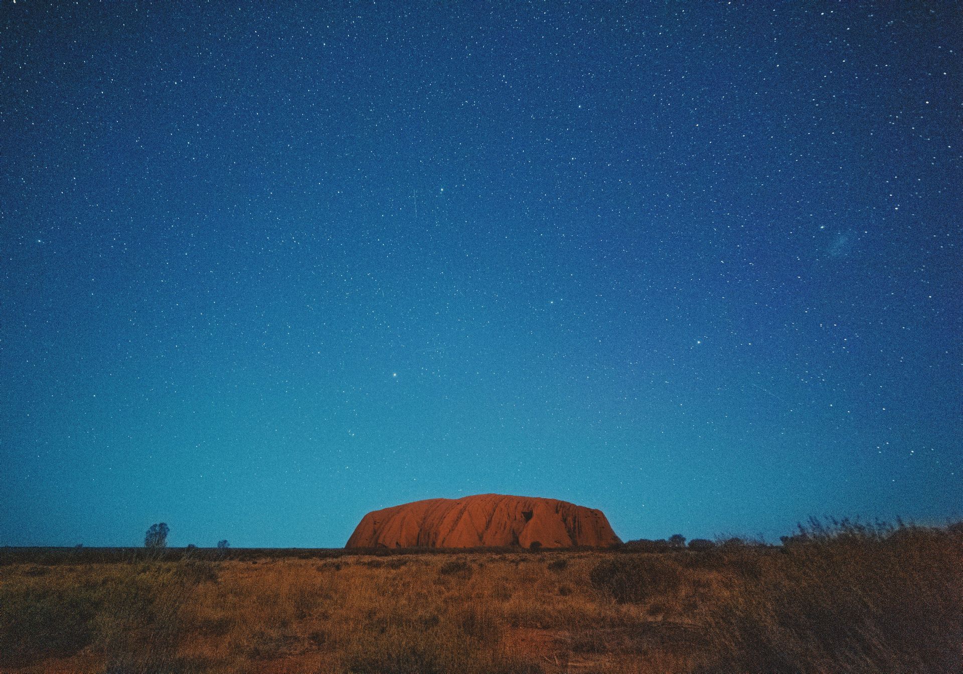 Uluru Rock formation in the middle of a desert at night in Australia.