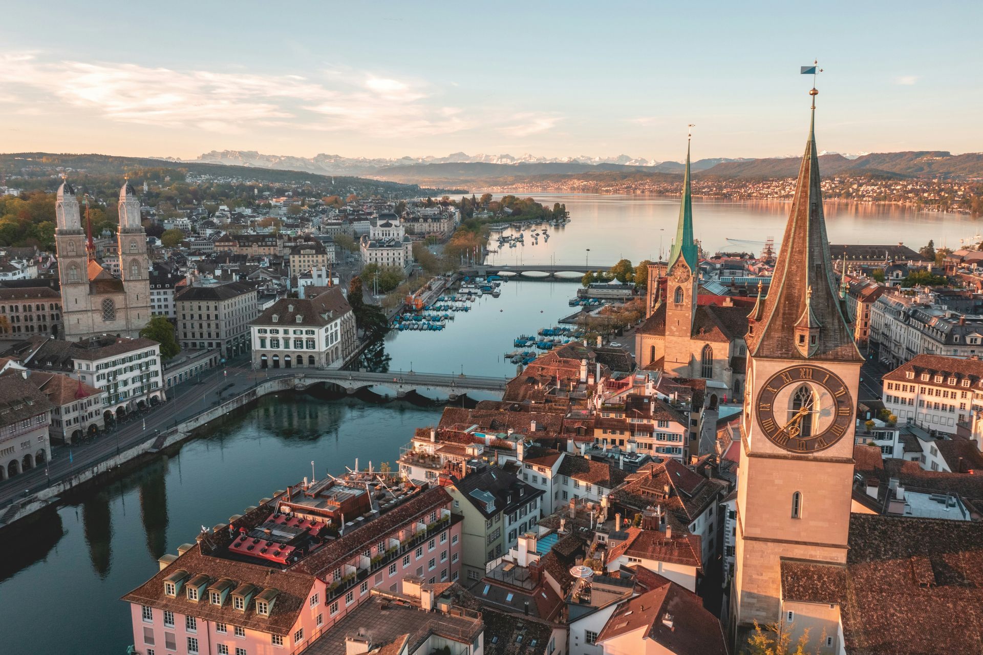 Zurich, Switzerland, aerial view. Cityscape with river, buildings, and church towers, bathed in warm sunlight.