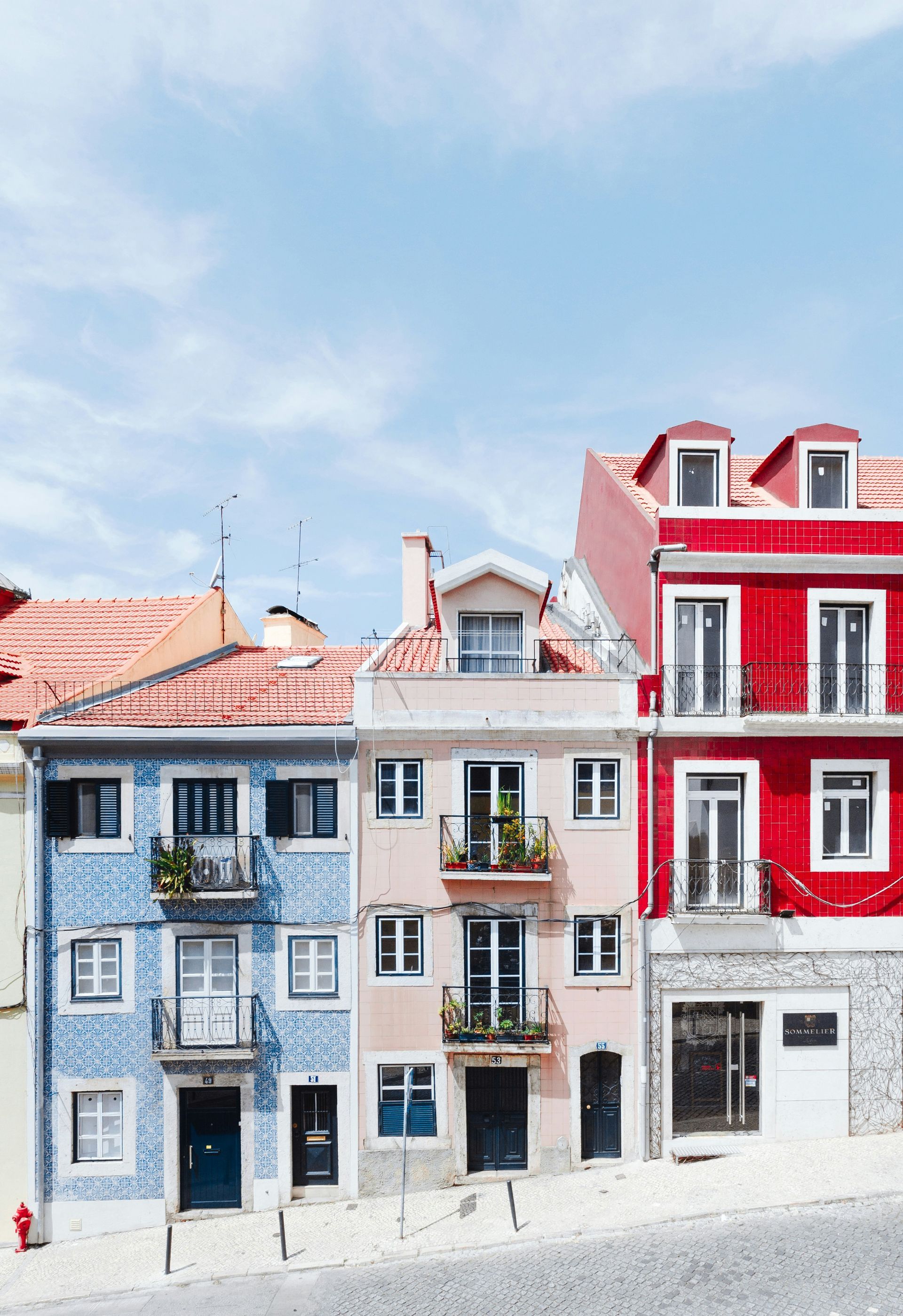Colorful buildings with blue, pink, and red facades on a cobblestone street in Lisbon, Portugal.