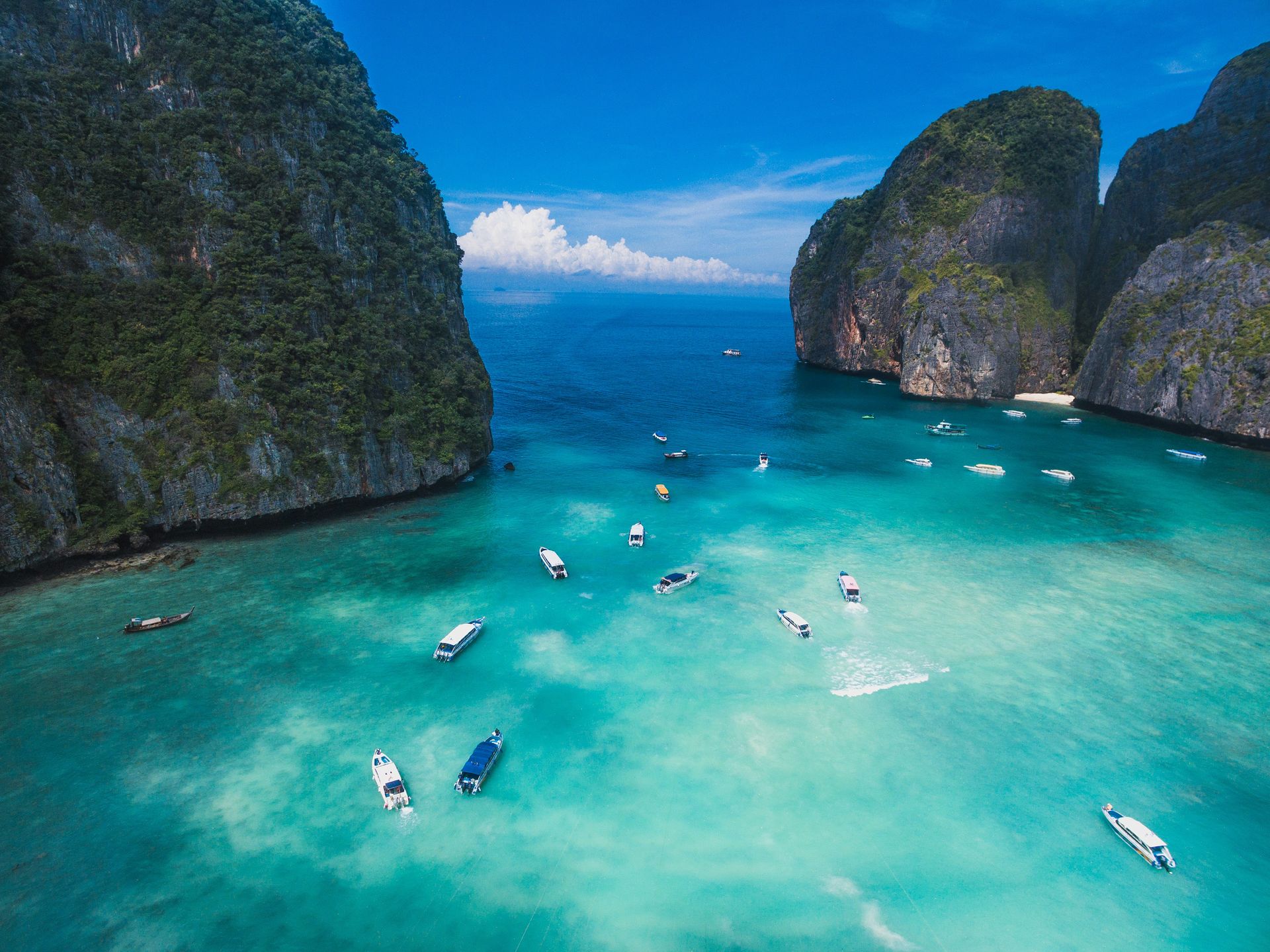 A group of boats are floating on top of a large body of water at the Phi Phi Islands in Krabi, Thailand.