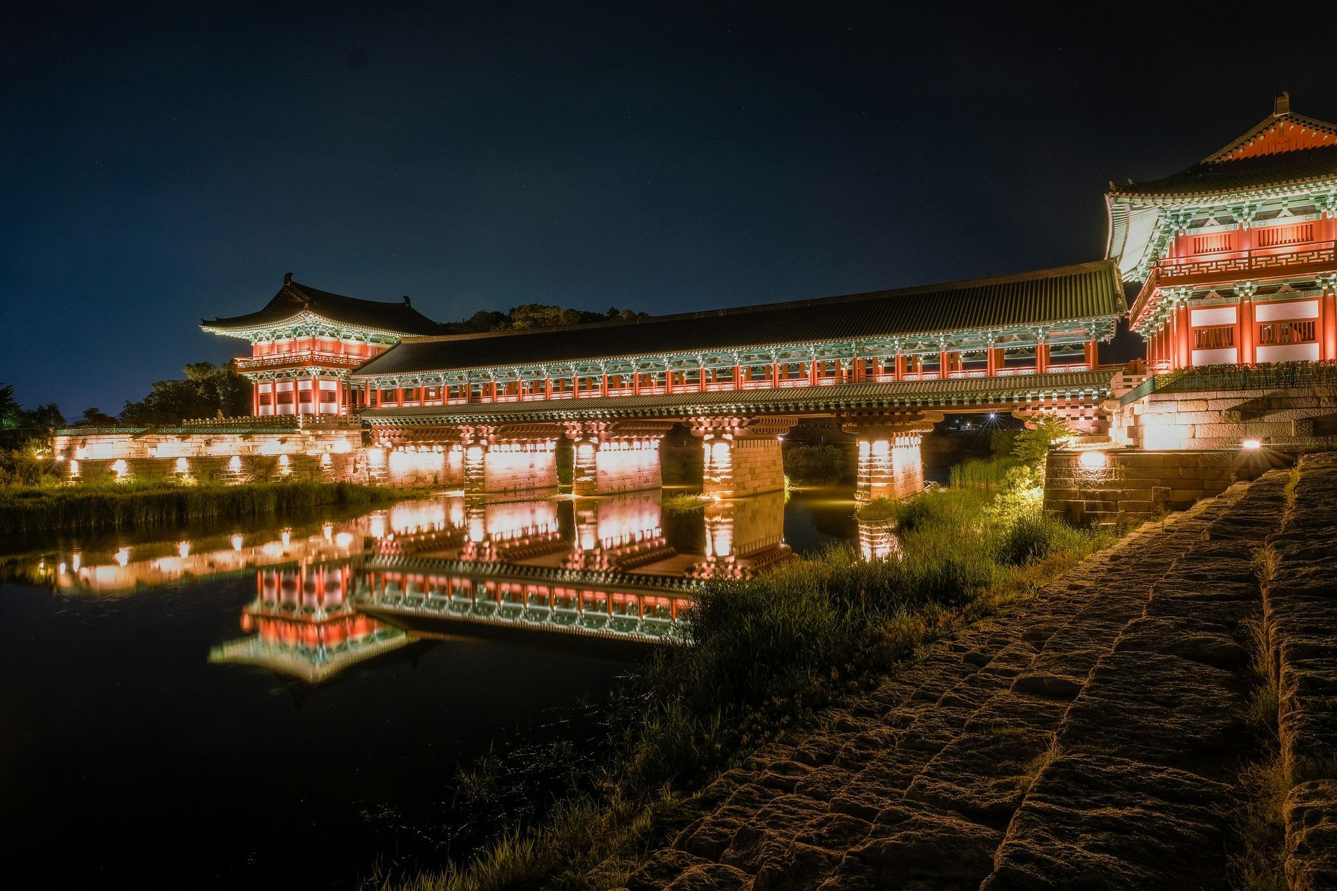 Lit up Korean bridge reflecting in water at night in Gyeongju, South Korea.
