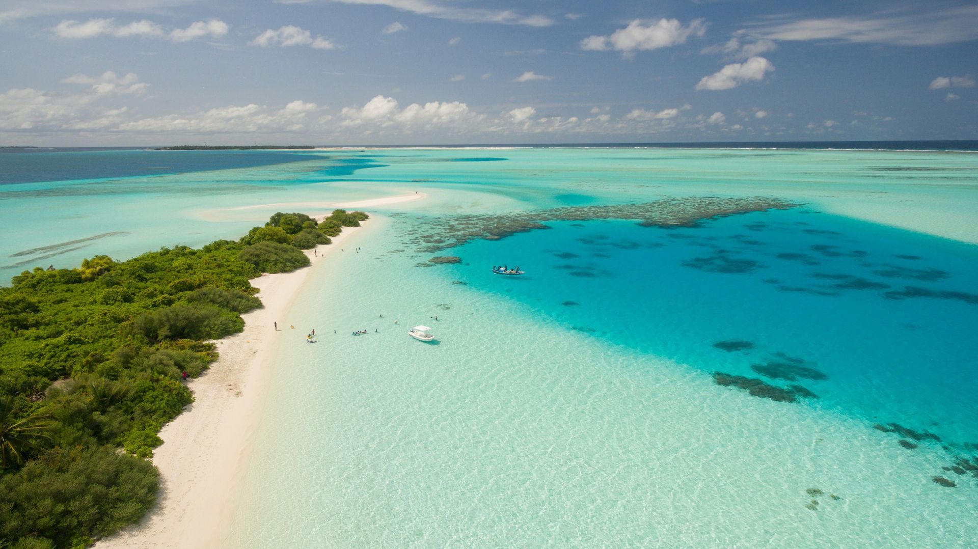 An aerial view of a tropical island with a white sandy beach and turquoise water.