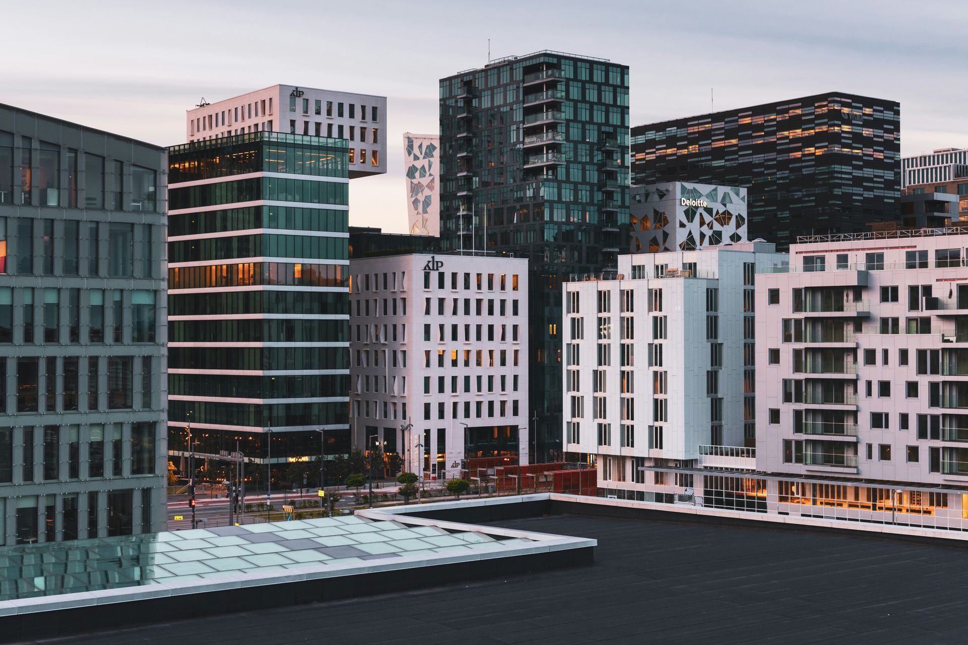Modern buildings in Oslo, Norway, with glass and white facades against a dusky sky.