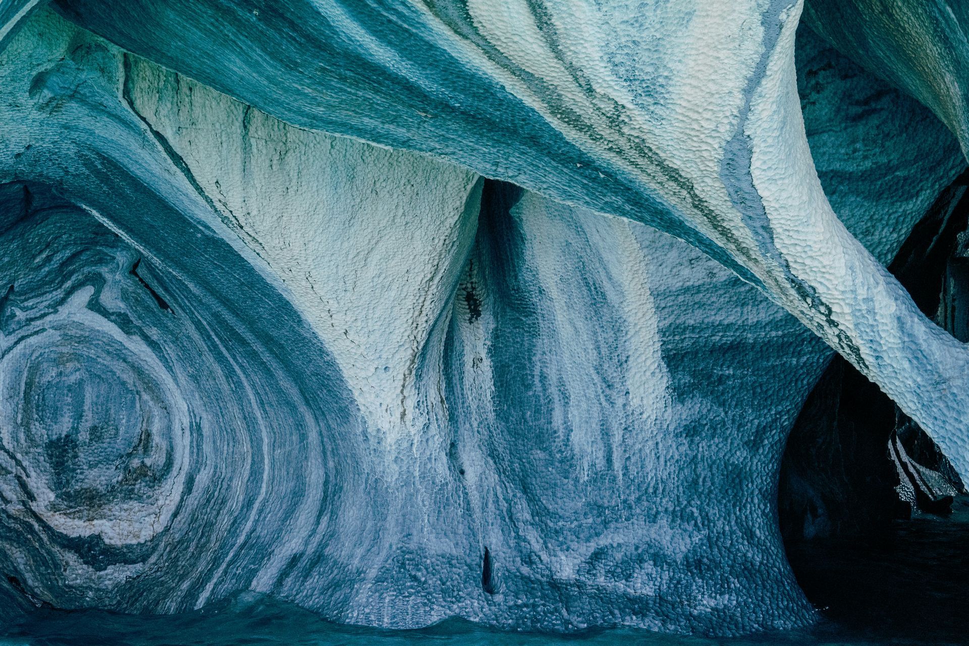 Swirling blue and white marble caves, reflecting in water in Aysén, Chile.