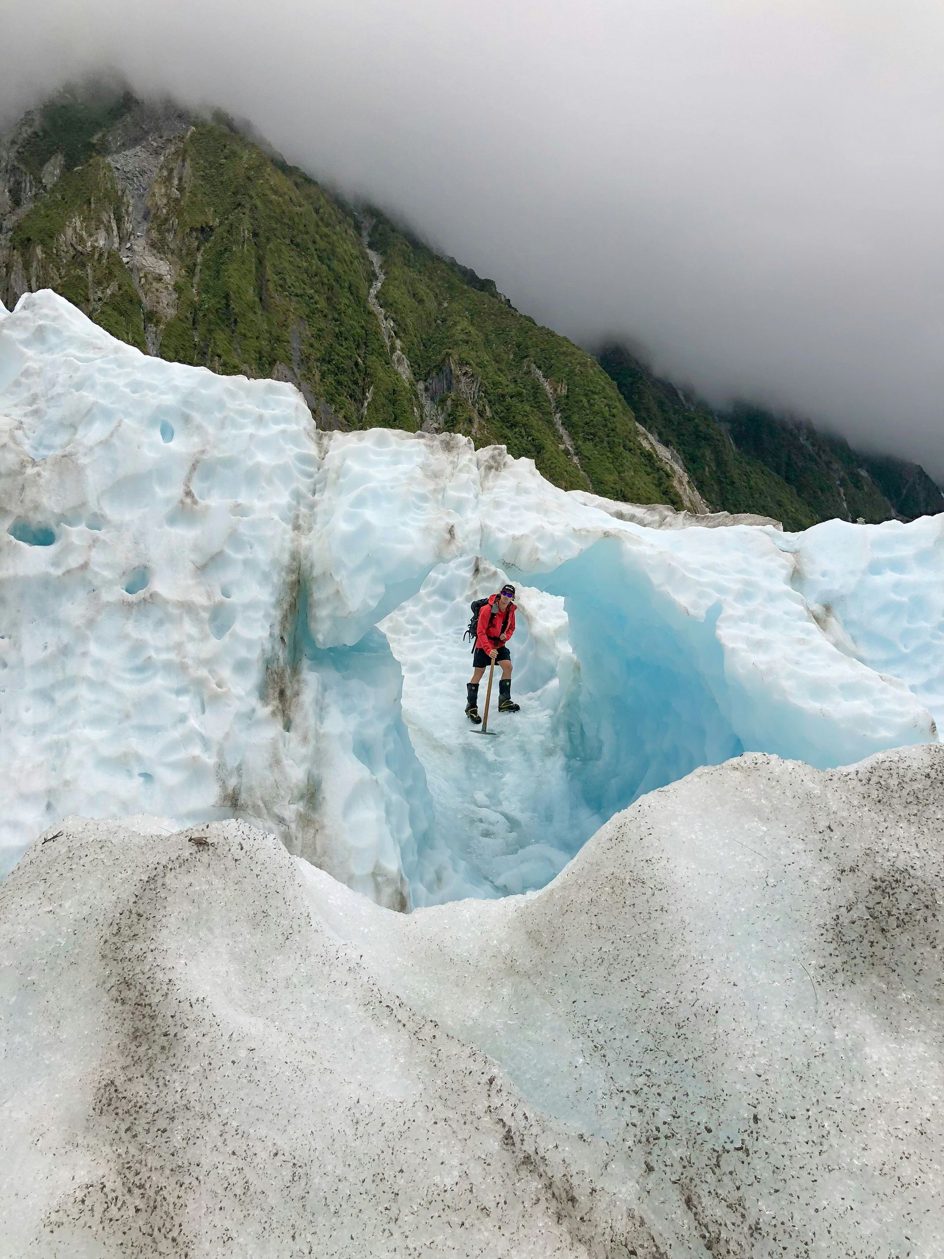 A person is standing on top of the Franz Josef Glacier, New Zealand.