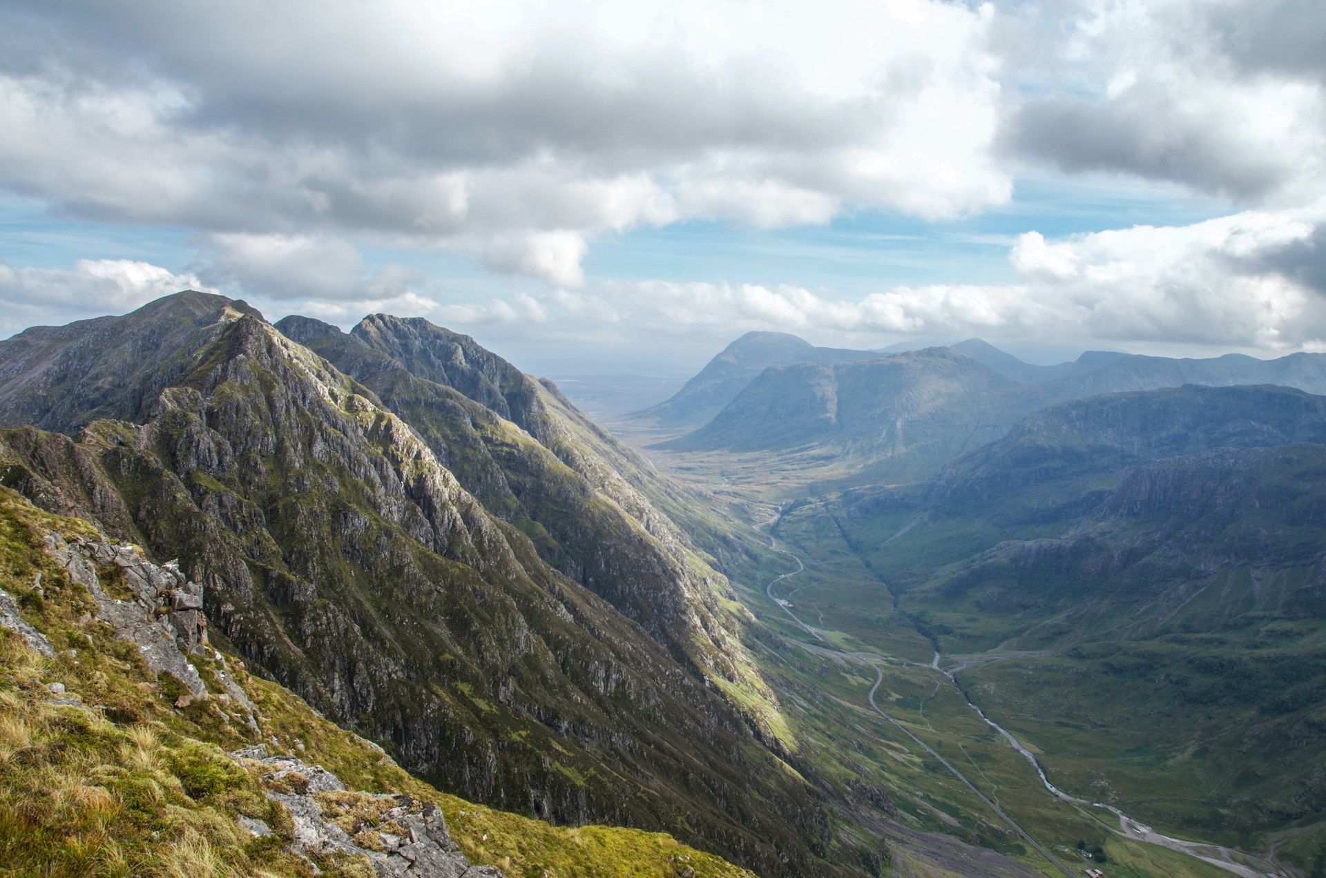 Mountains and valley under a cloudy sky. Green and rocky landscape in Glencoe, Scotland.