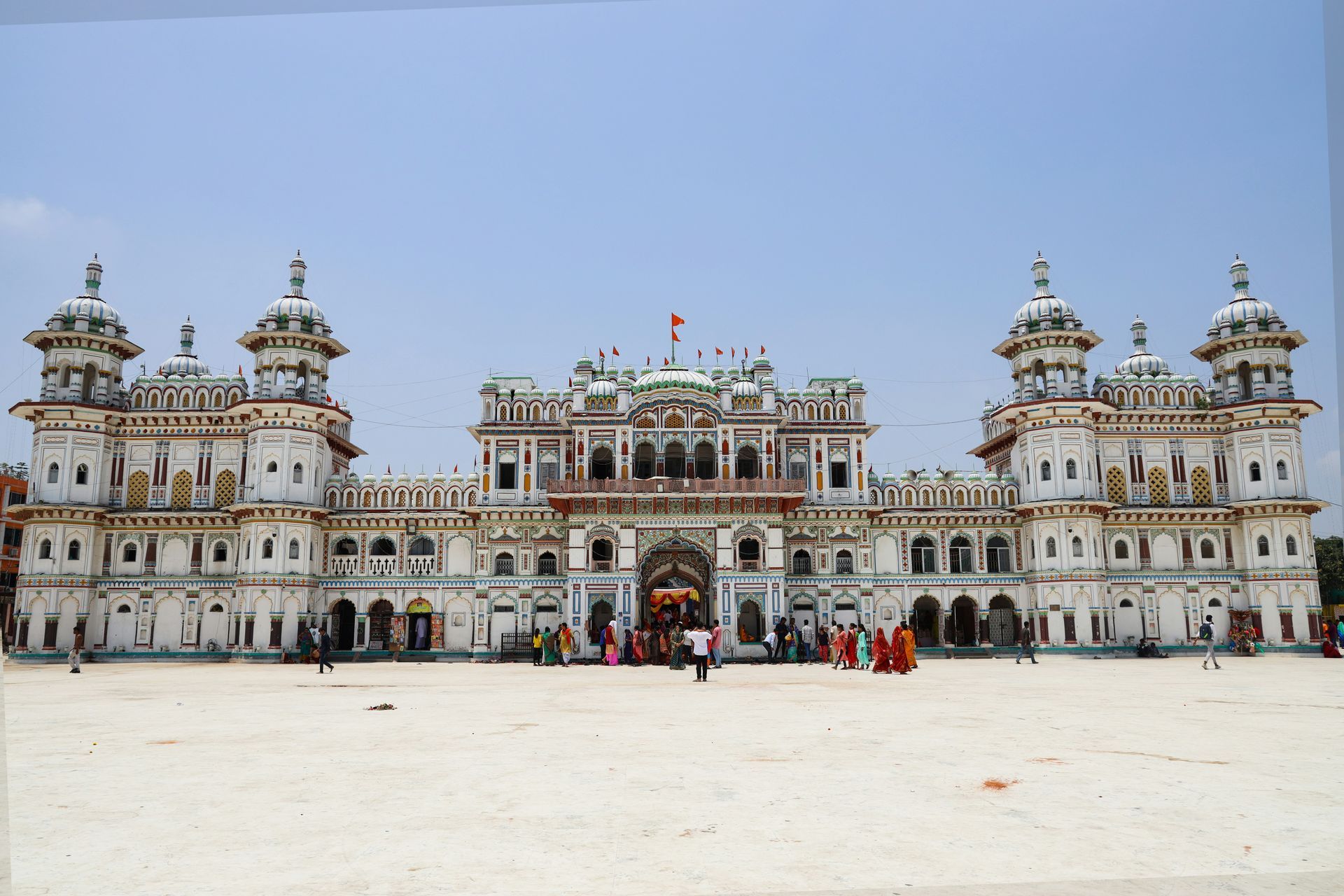 White ornate temple with multiple towers, people gathered in the courtyard in Janakpur, Nepal.