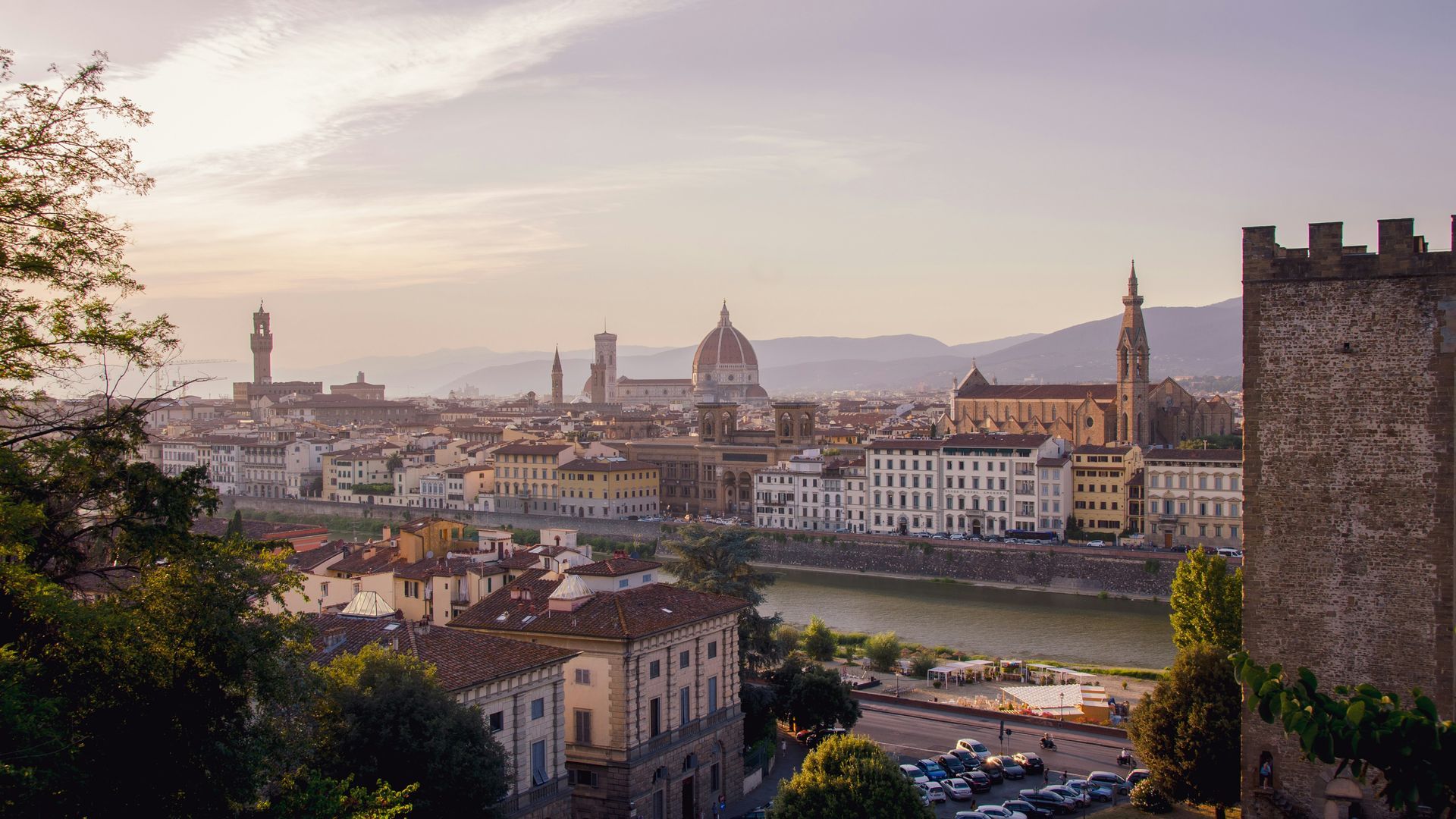 An aerial view of Florence with a river in the foreground and a castle in the background.