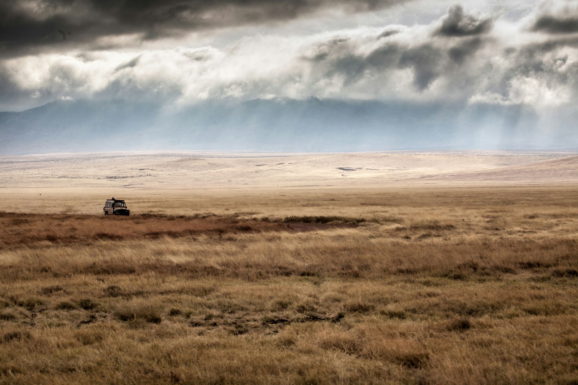 A car is parked in the middle of a desert in Ngorongoro, Tanzania.
