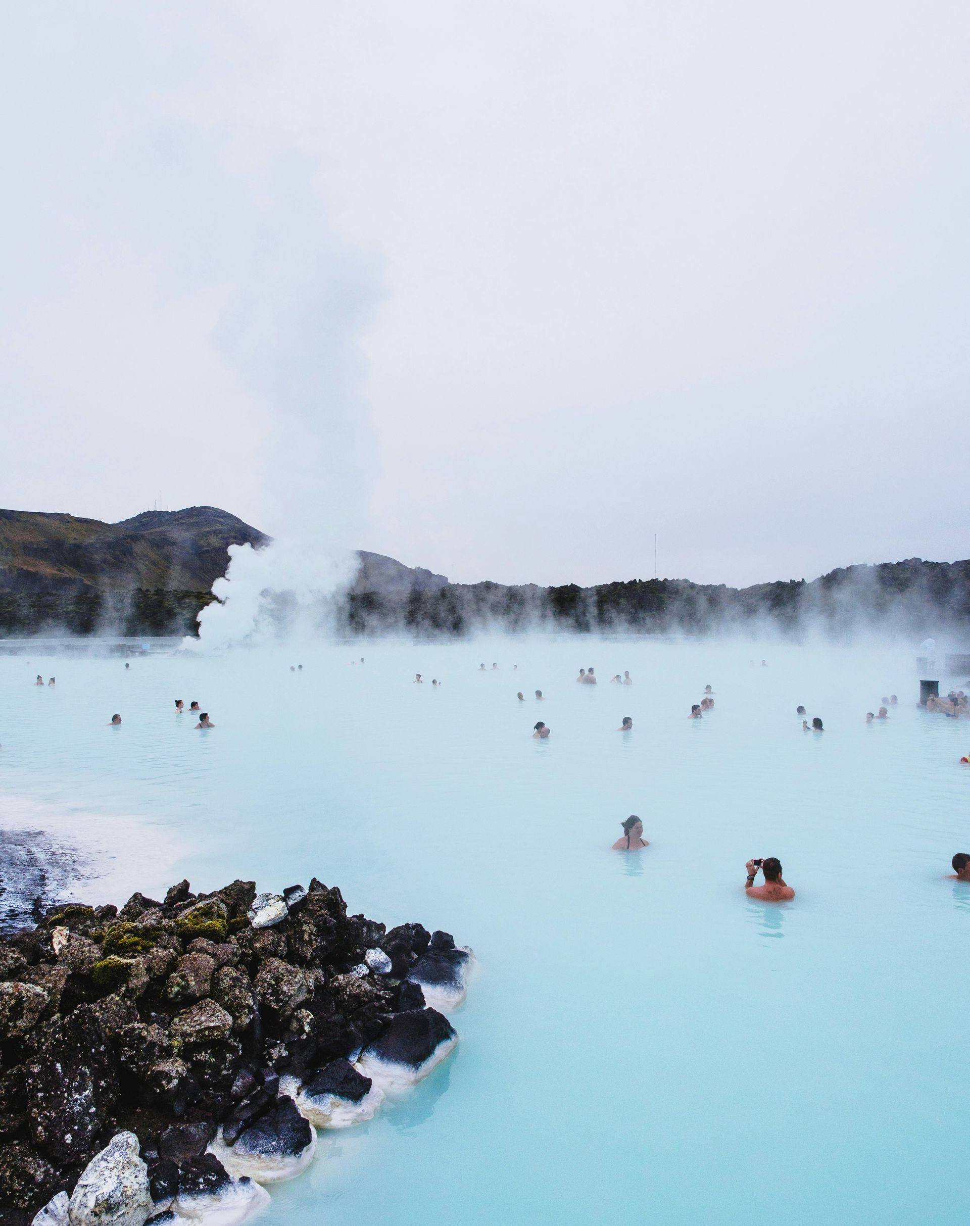 People bathing in the Blue Lagoon, Iceland's geothermal spa with turquoise water and misty surroundings.