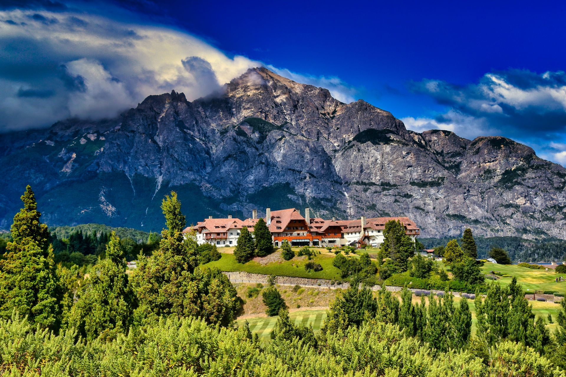 Large building nestled amongst trees against a backdrop of a mountain in San Carlos de Bariloche, Argentina.