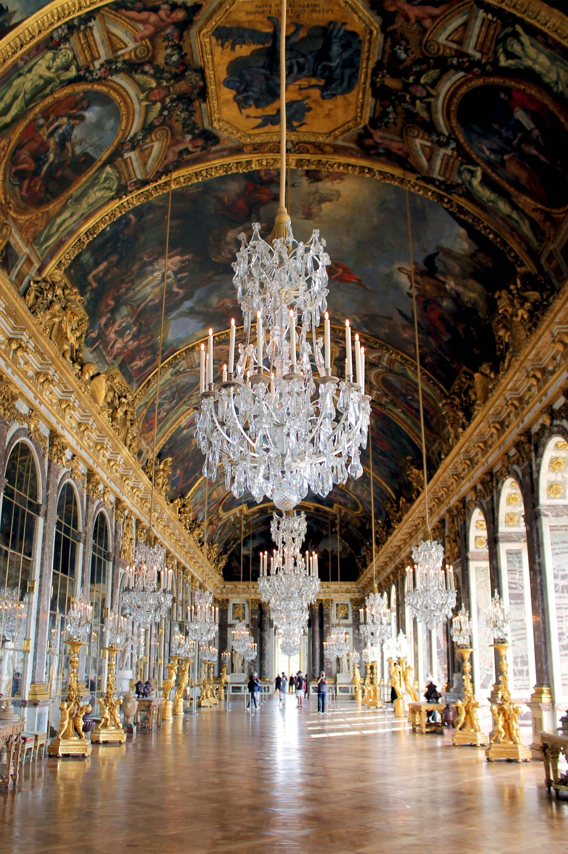 A large room with a lot of chandeliers hanging from the ceiling at the Palace of Versailles in France.