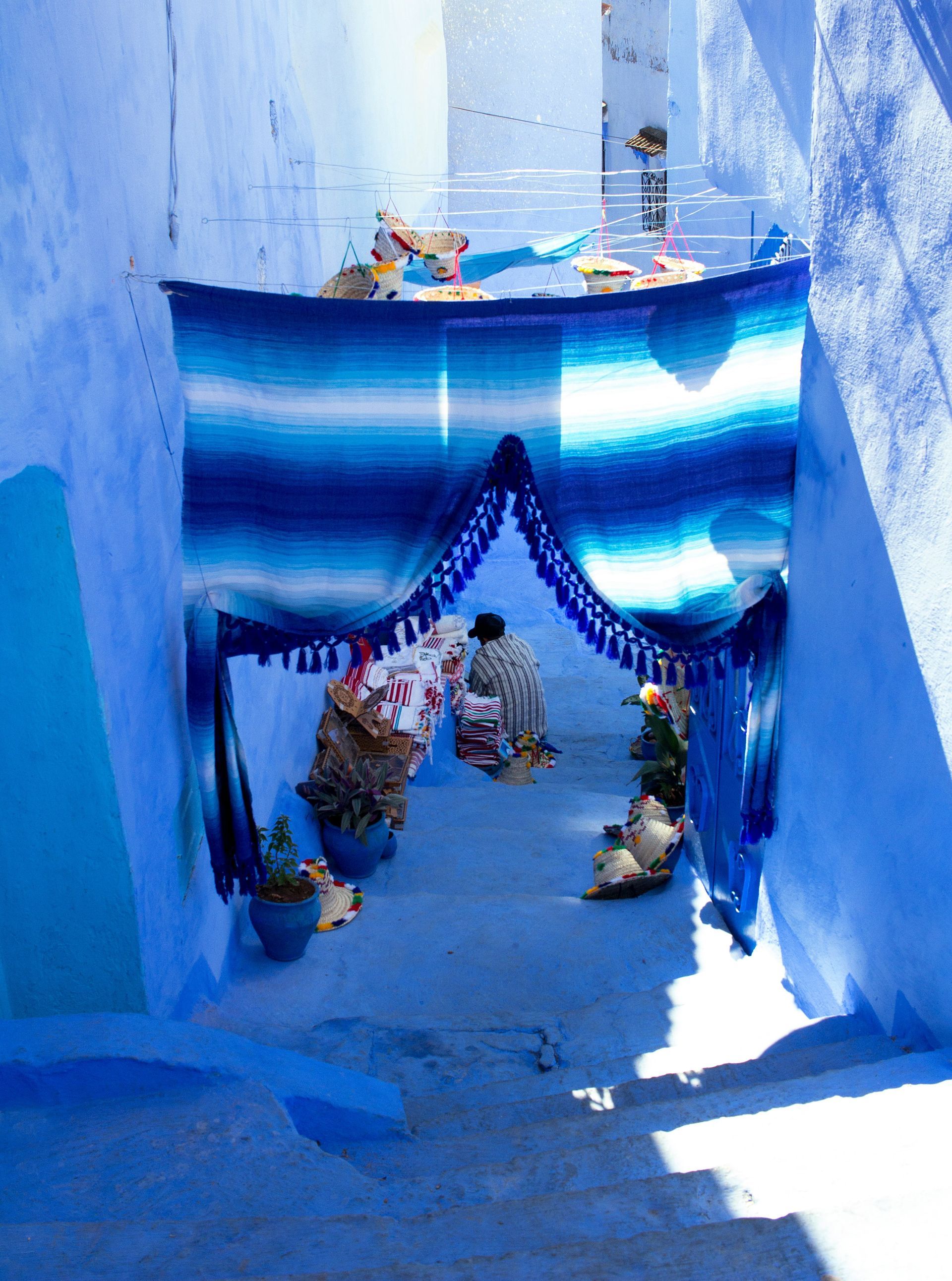A narrow alleyway with blue walls and a blue blanket in Chefchaouen, Morocco.