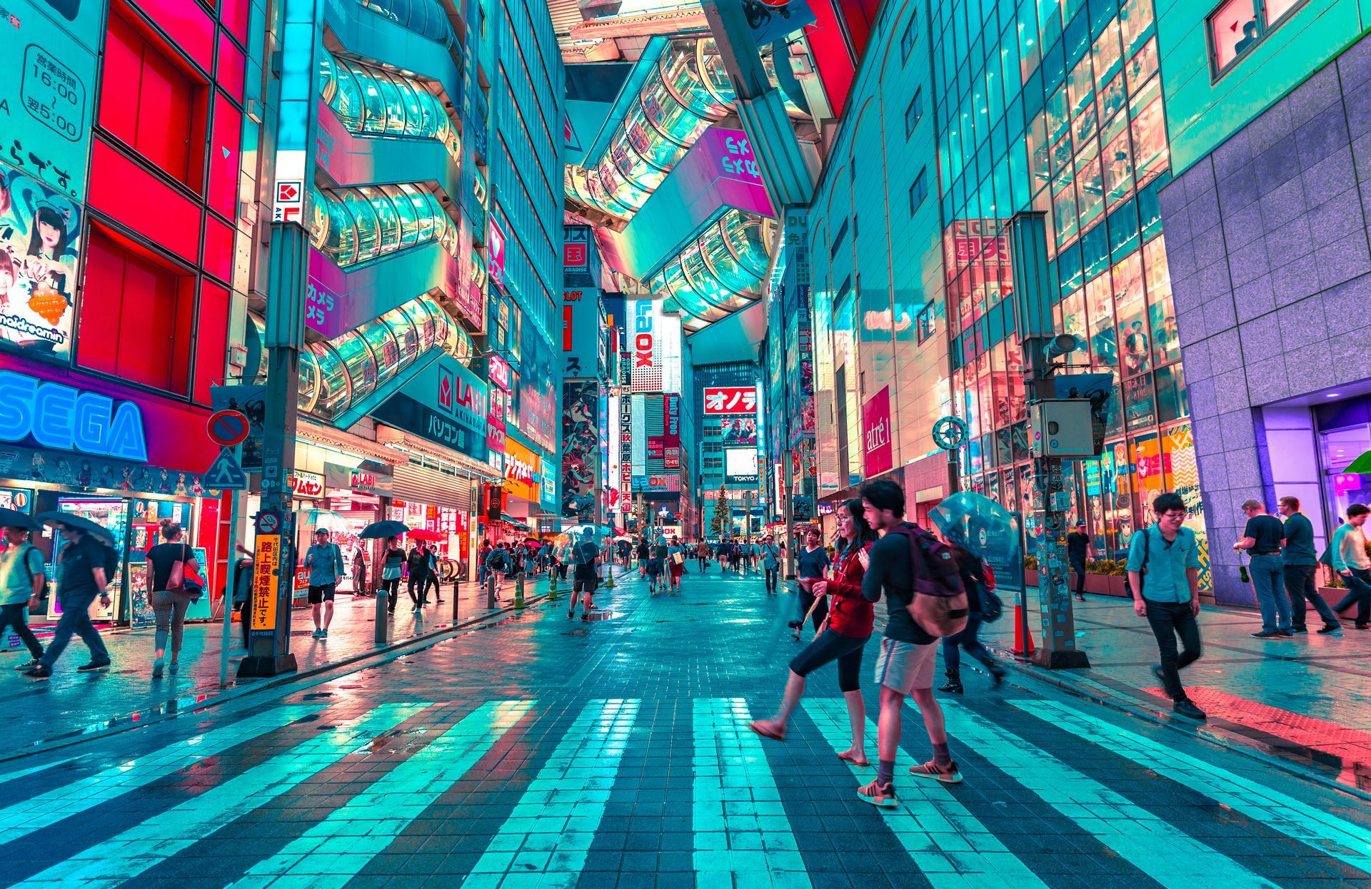 Bright, neon-lit street in Tokyo with people walking on a crosswalk; colorful buildings and signs overhead.