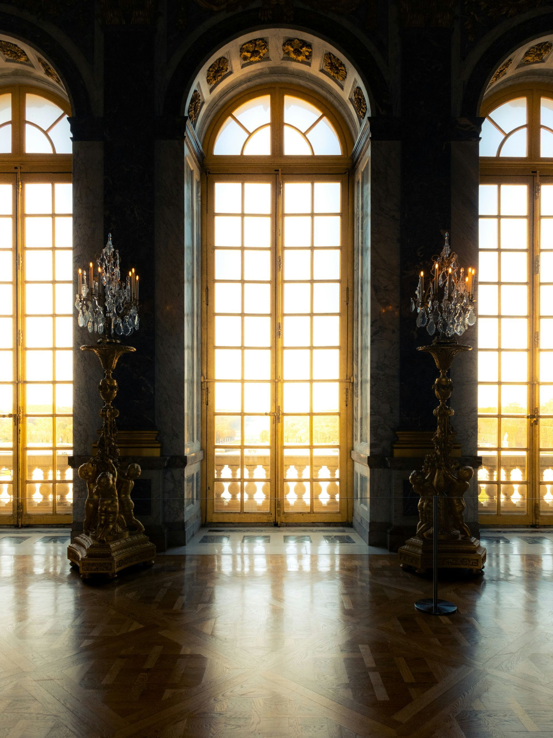 A room with a lot of windows and candles at the Palace of Versailles in France.