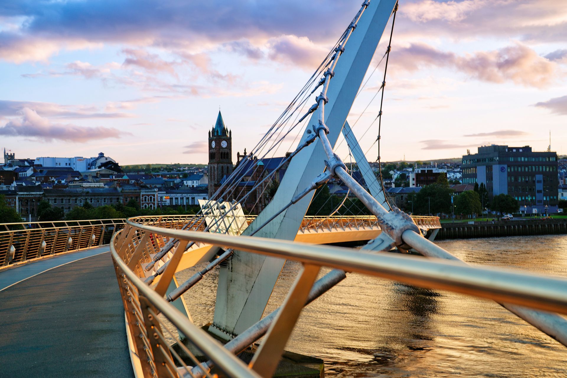 Bridge over water at sunset with city skyline in the background in Londonderry, Northern Ireland.