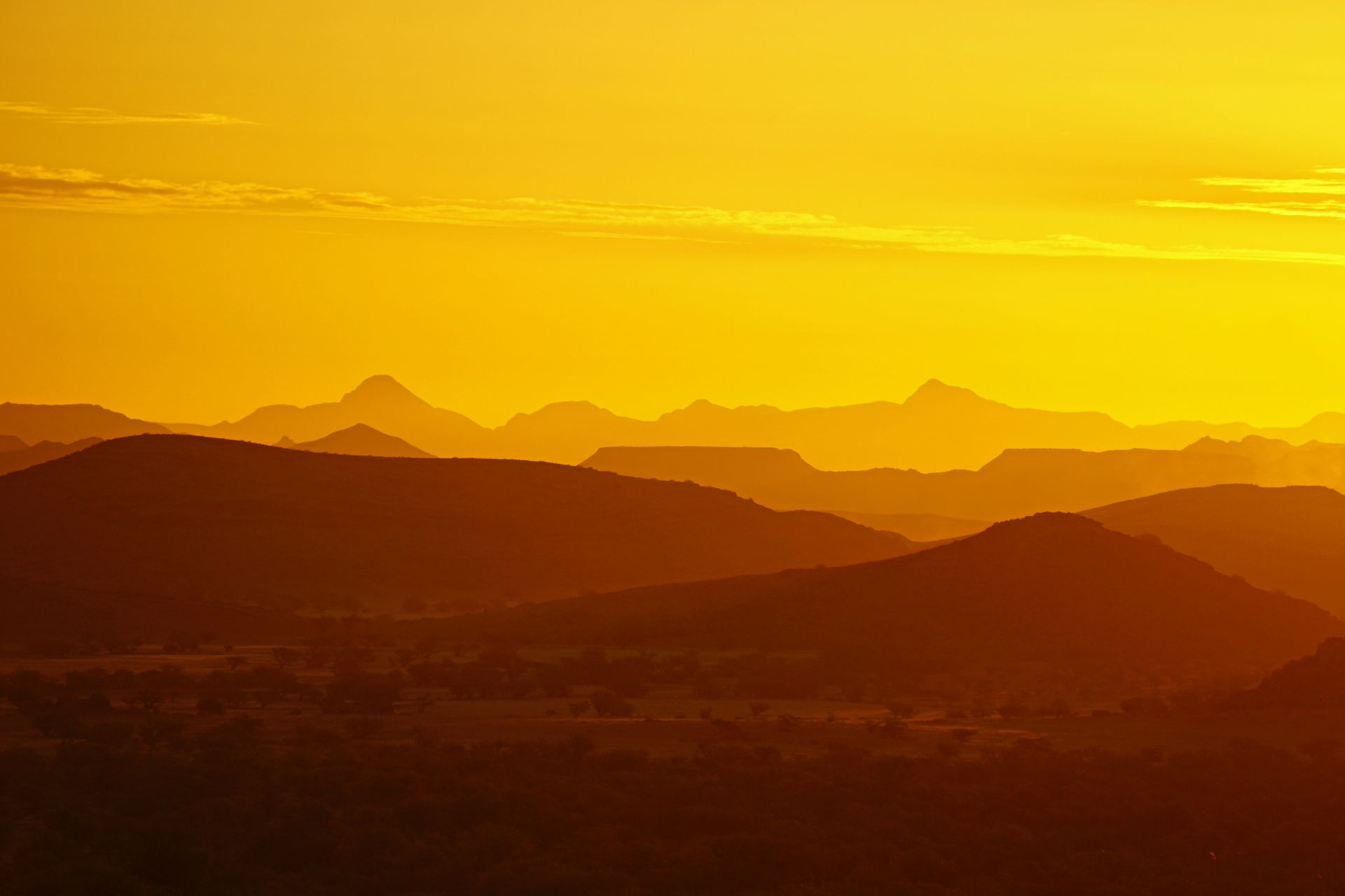 Silhouetted mountain range against a golden sunset sky in Damaraland, Namibia.