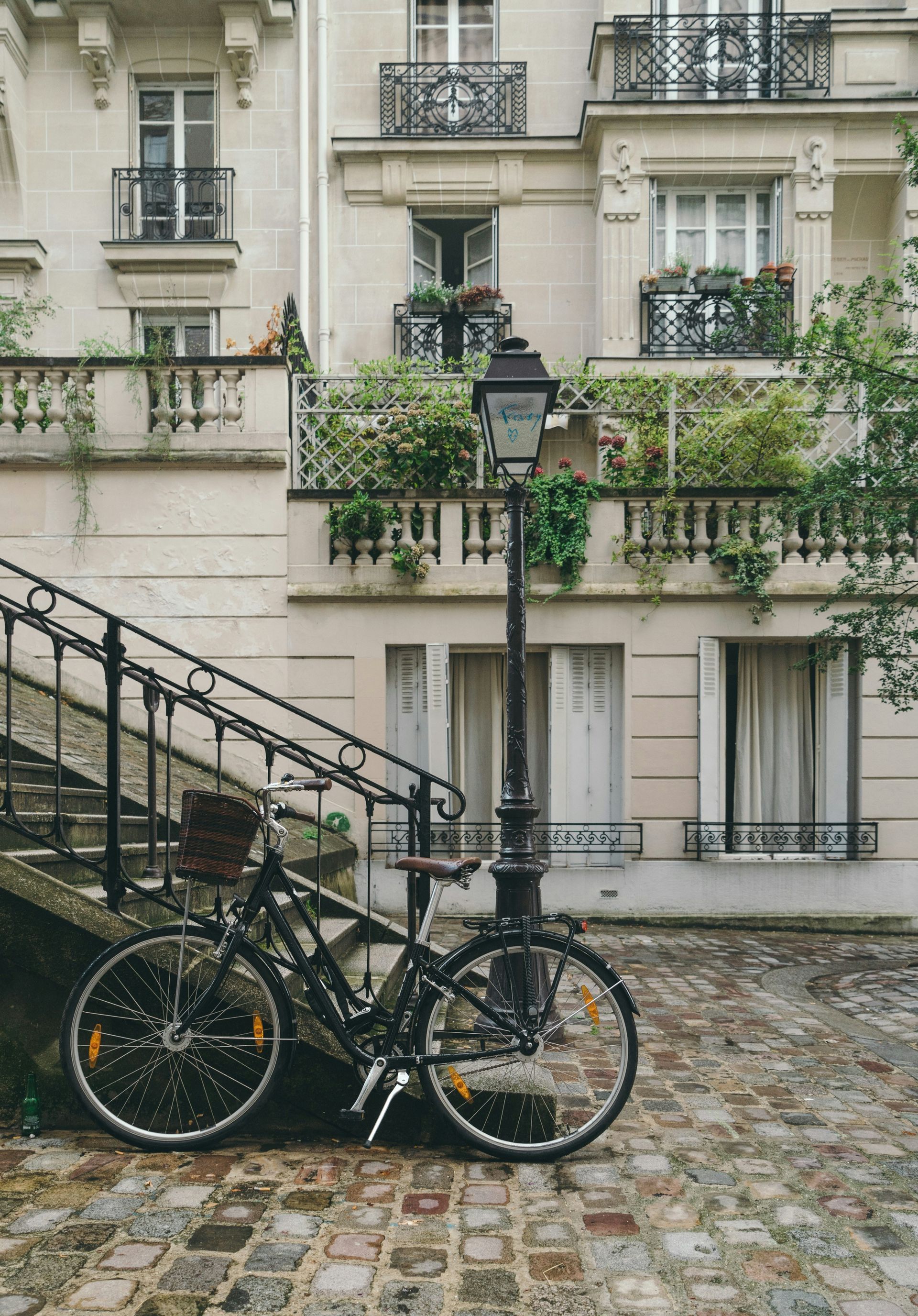 Two bicycles are parked on the sidewalk in front of a building in Paris, France.
