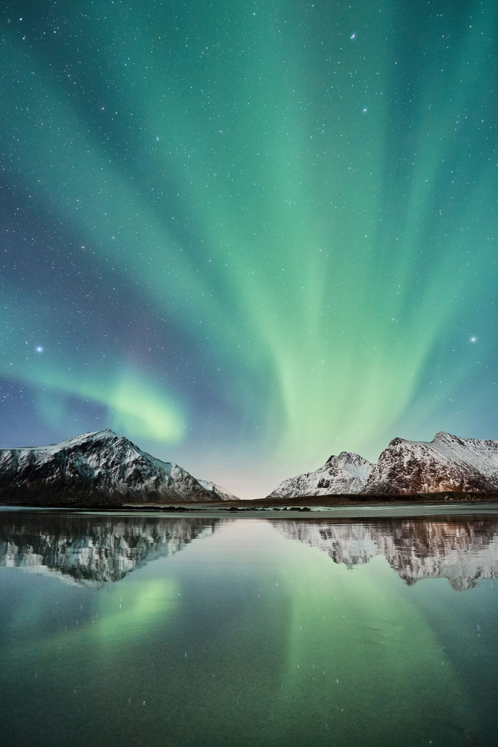 The aurora borealis is reflected in the water of a lake in Norway.
