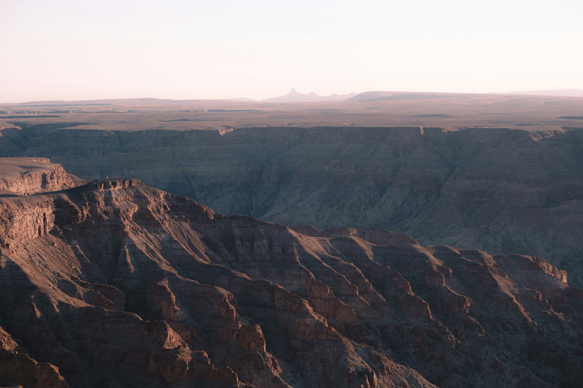 Fish River Canyon landscape at dawn, with layered rock formations and a distant horizon in Namibia.