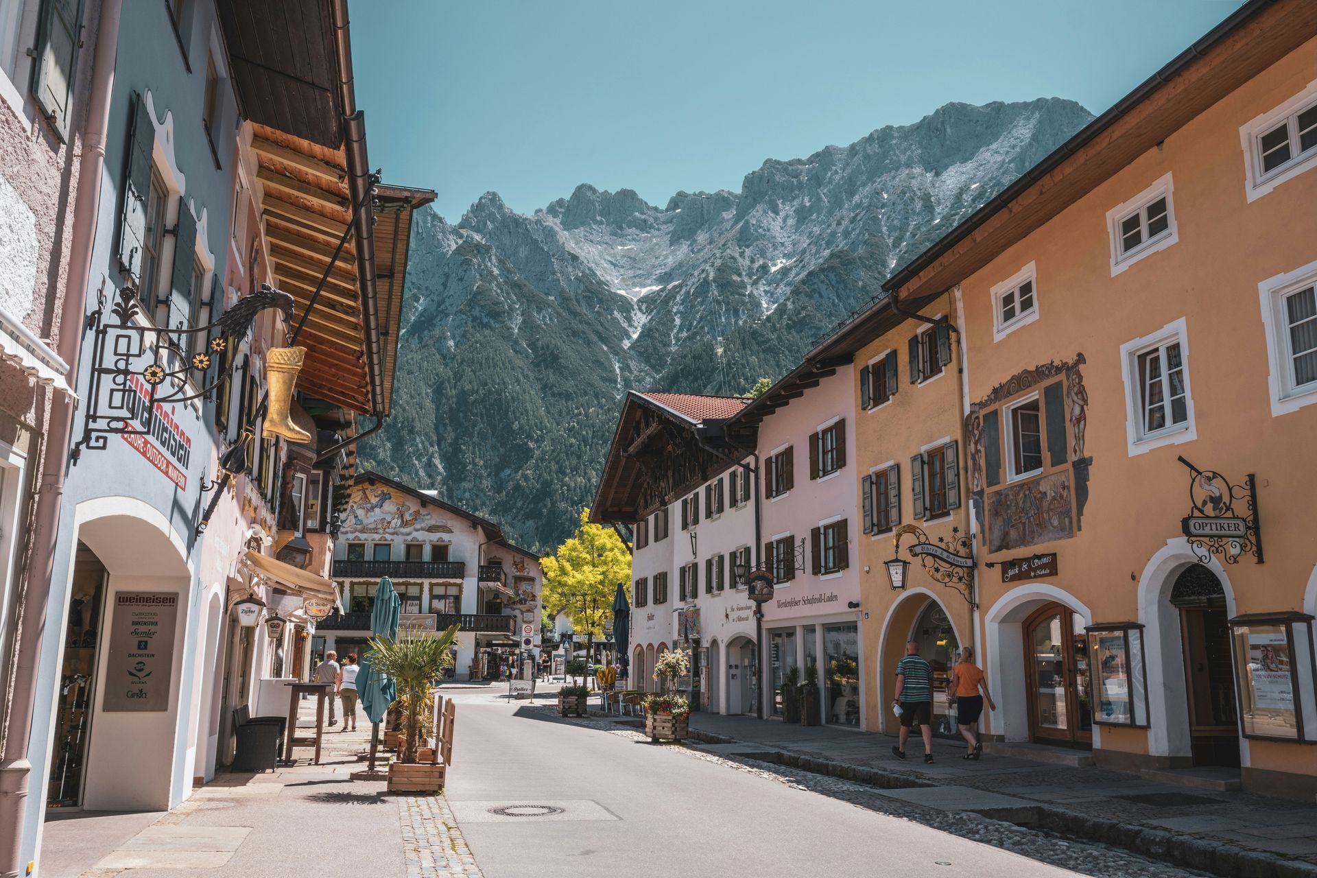 Street with colorful buildings, shops, and a mountain backdrop in Mittenwald, Germany.