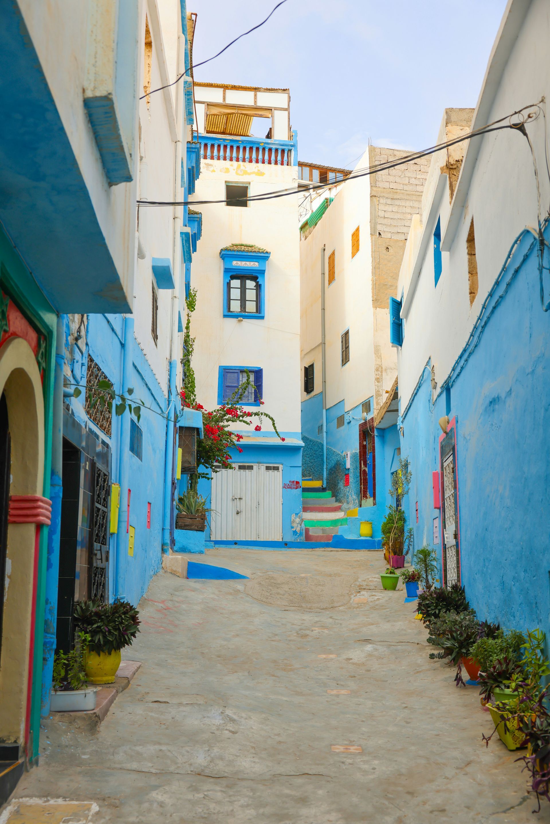 A narrow alleyway between two blue and white buildings in Taghazout, Morocco.
