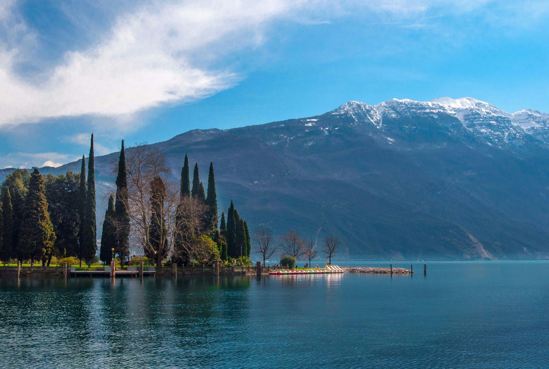 A small island in the middle of Lake Garda with mountains in the background in Italy.