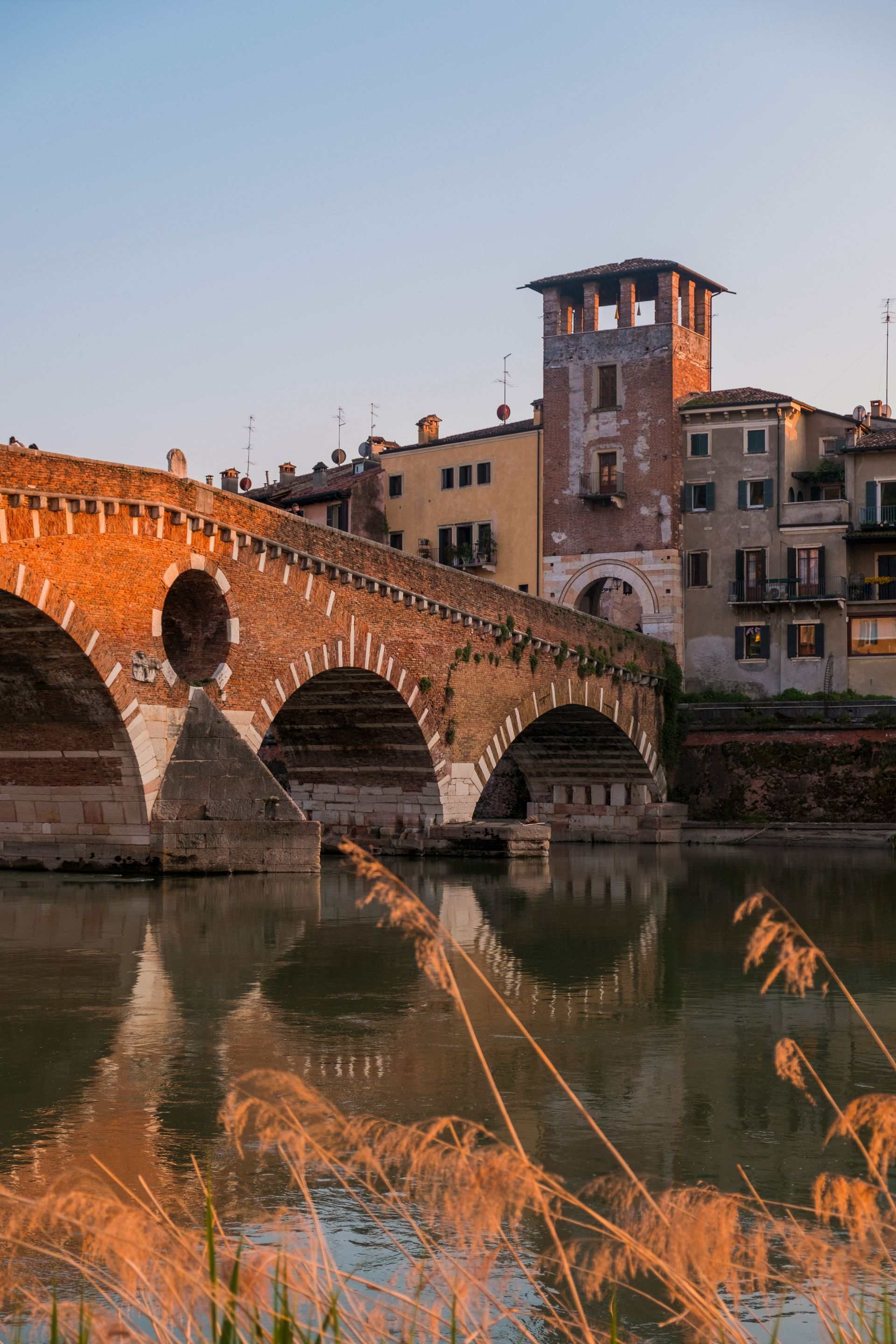A bridge over a body of water with buildings in the background in Verona, Italy.