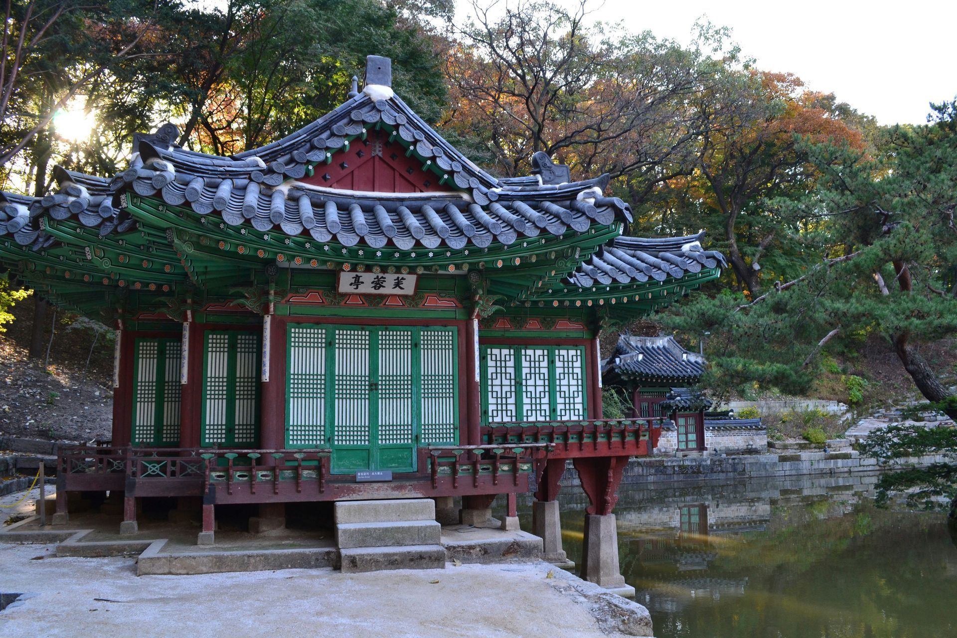 Korean pavilion with tiled roof and green accents, set by a pond at Changdeokgung, South Korea.