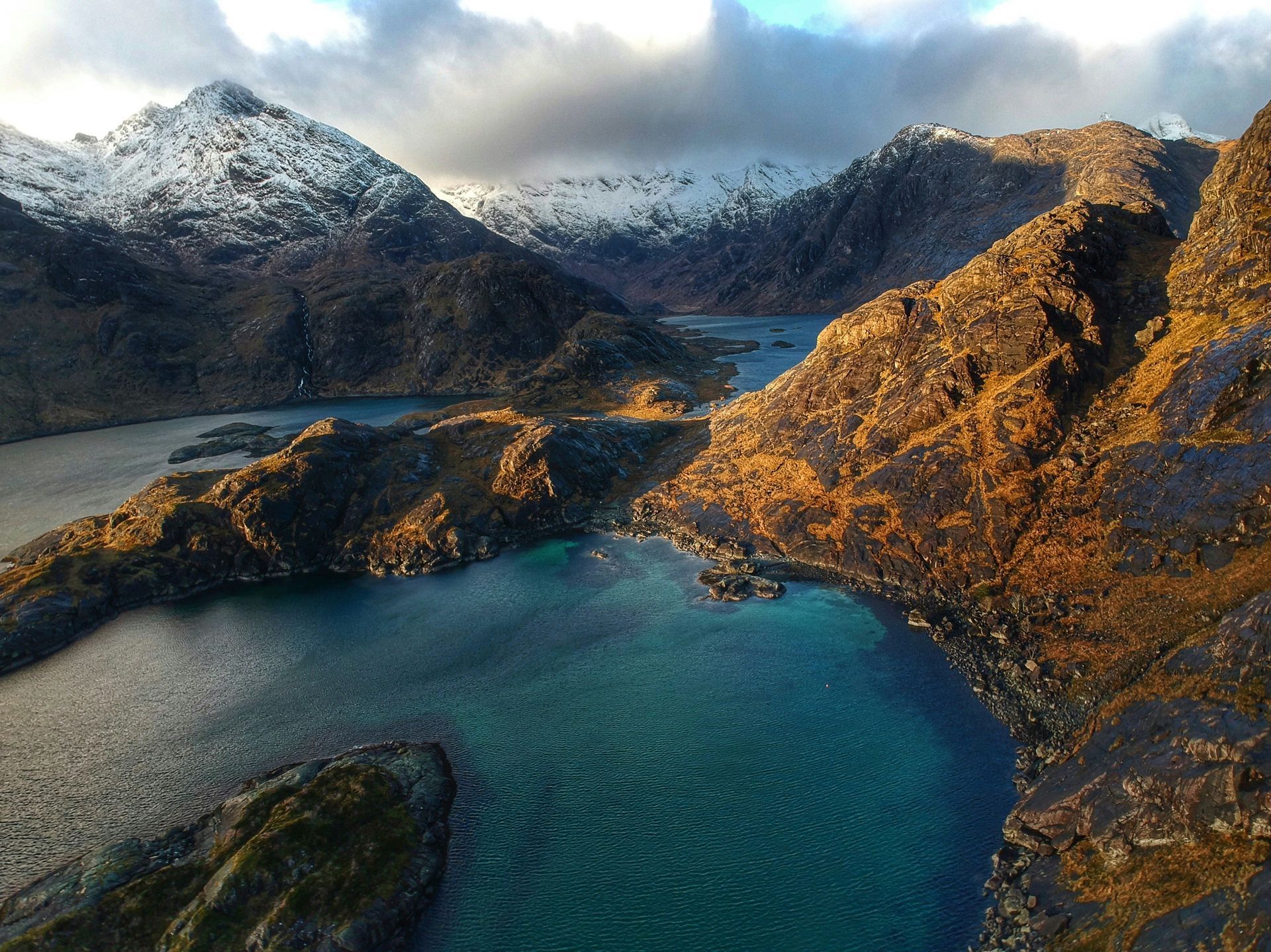 Loch in the Scottish Highlands surrounded by rugged mountains, some snow-capped on the Isle of Skye, Scotland.