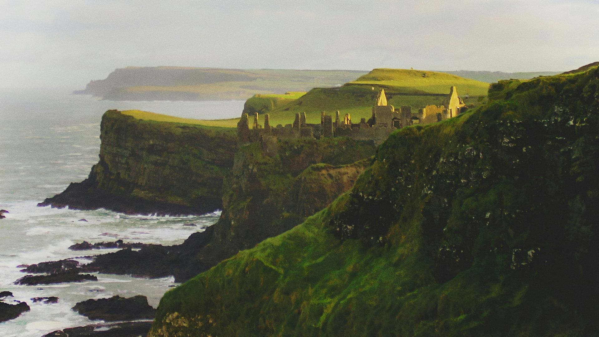 Coastal cliffs with Dunluce Castle overlook a gray sea in Northern Ireland.