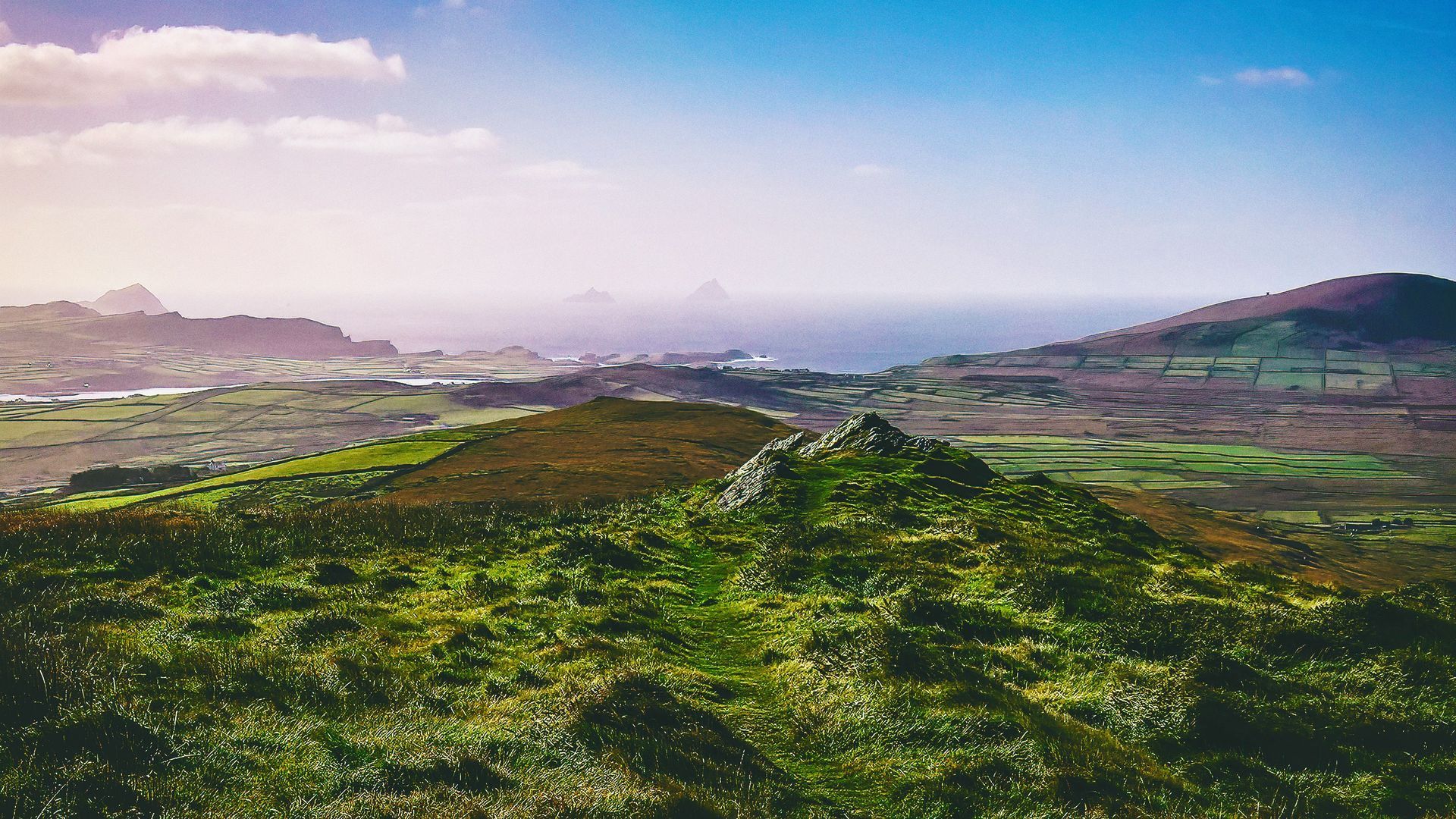 Rolling green hills overlooking a coastal landscape on the Ring of Kerry, Ireland.