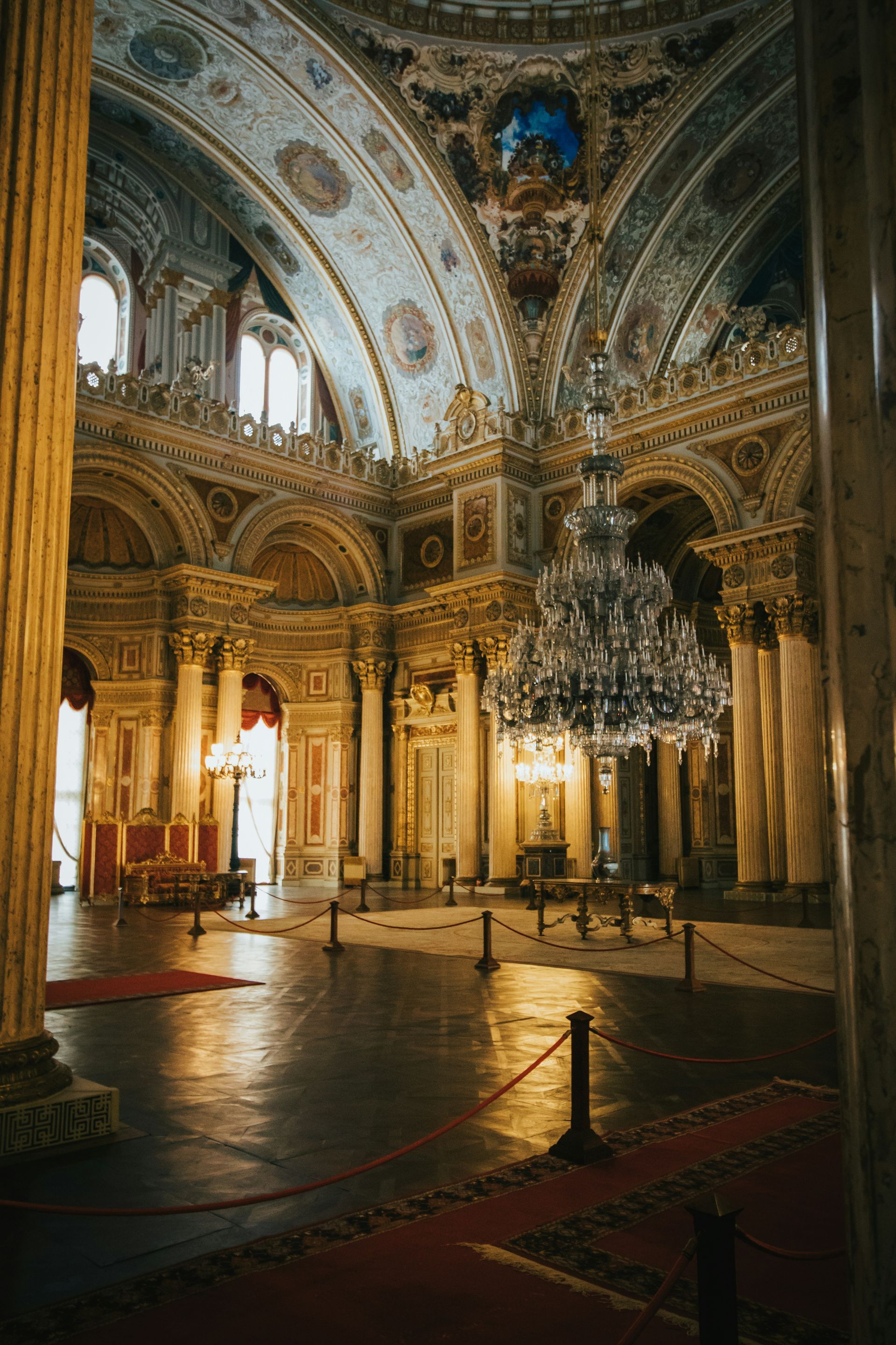 Opulent palace interior: gold columns, ornate ceiling, large chandelier, red carpet in Istanbul, Turkey.