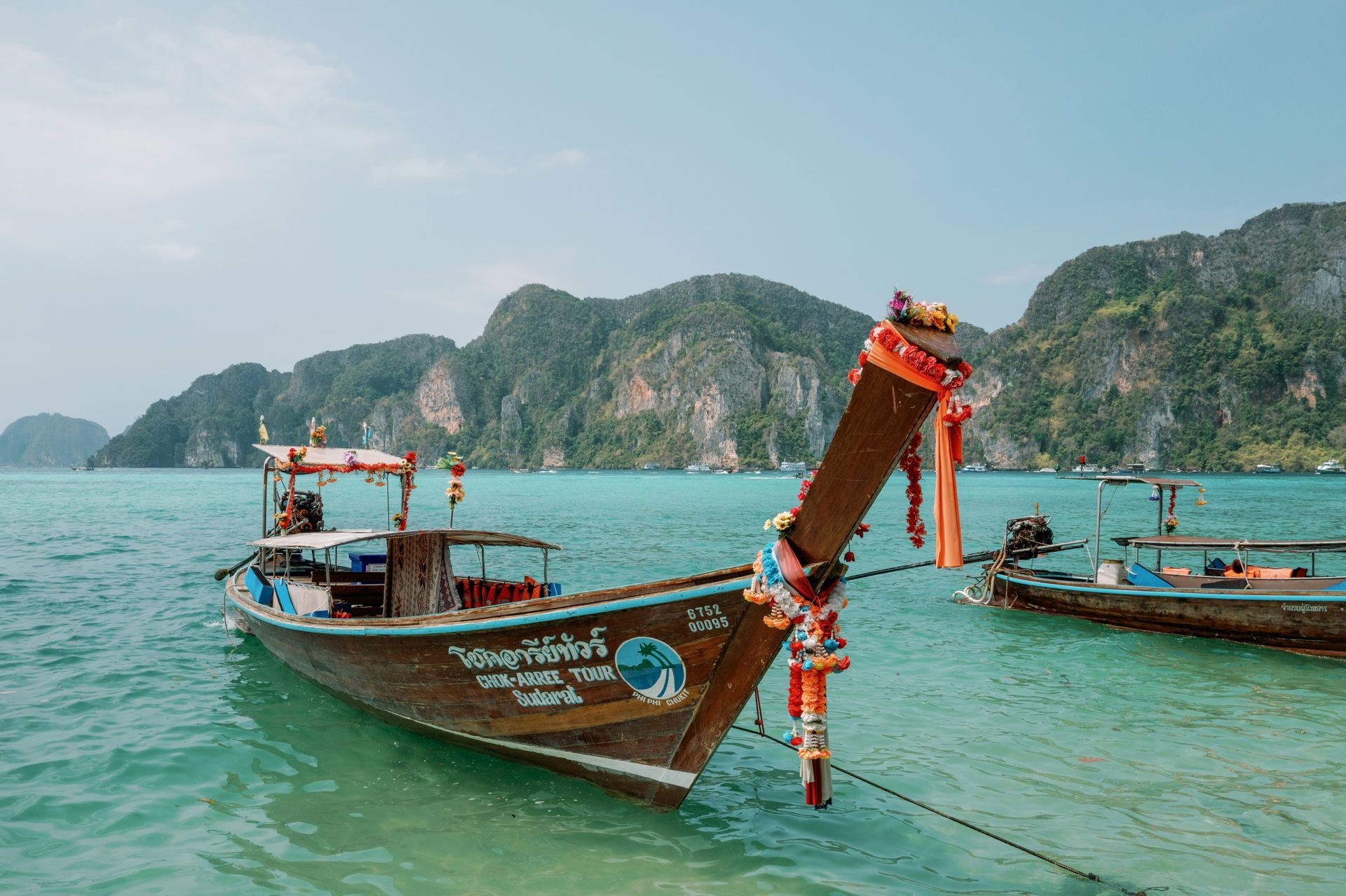 A boat is floating on top of a body of water with the Phi Phi Islands in the background in Krabi, Thailand.