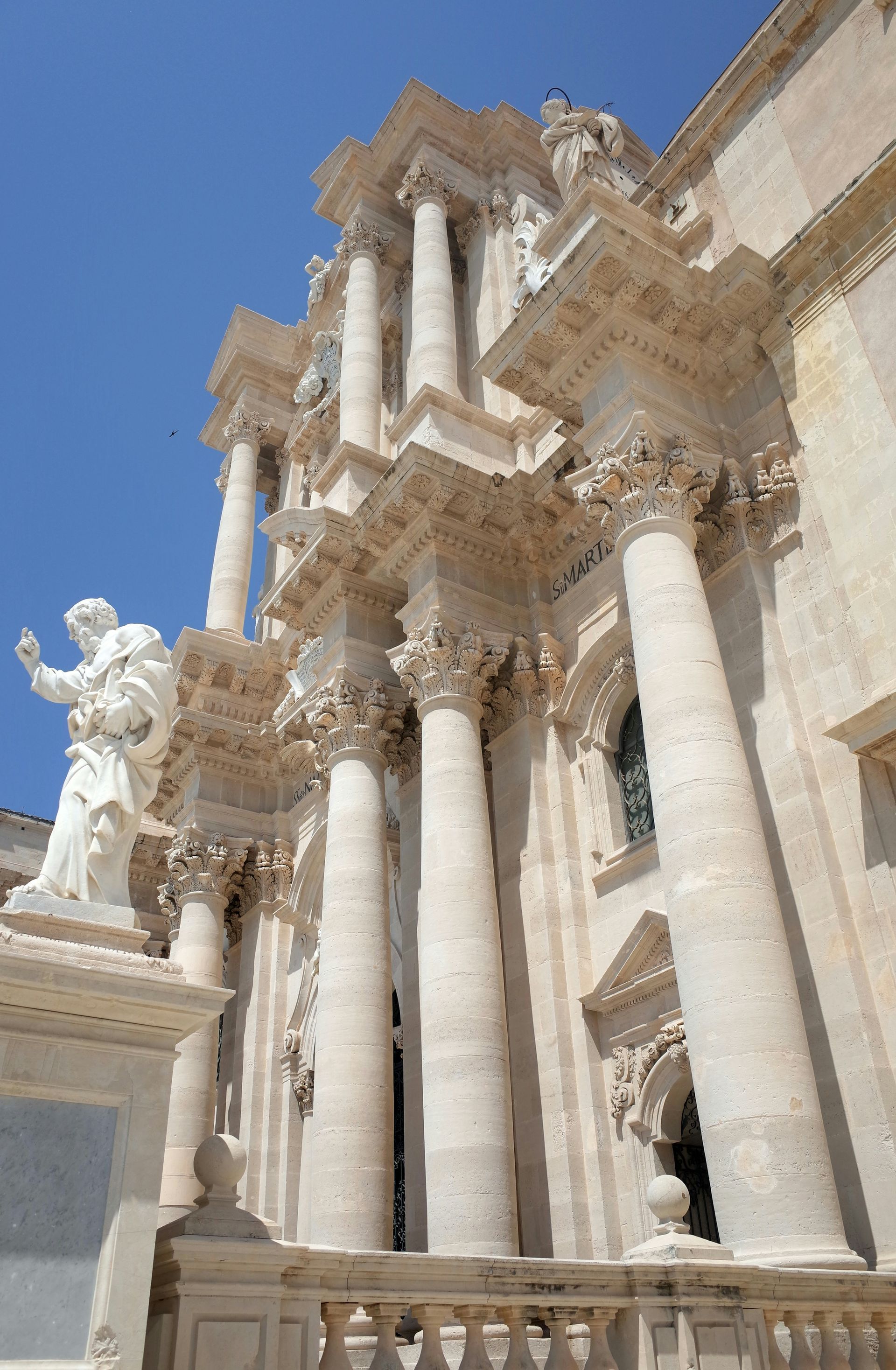 A large building with columns and statues on it in Sicily.