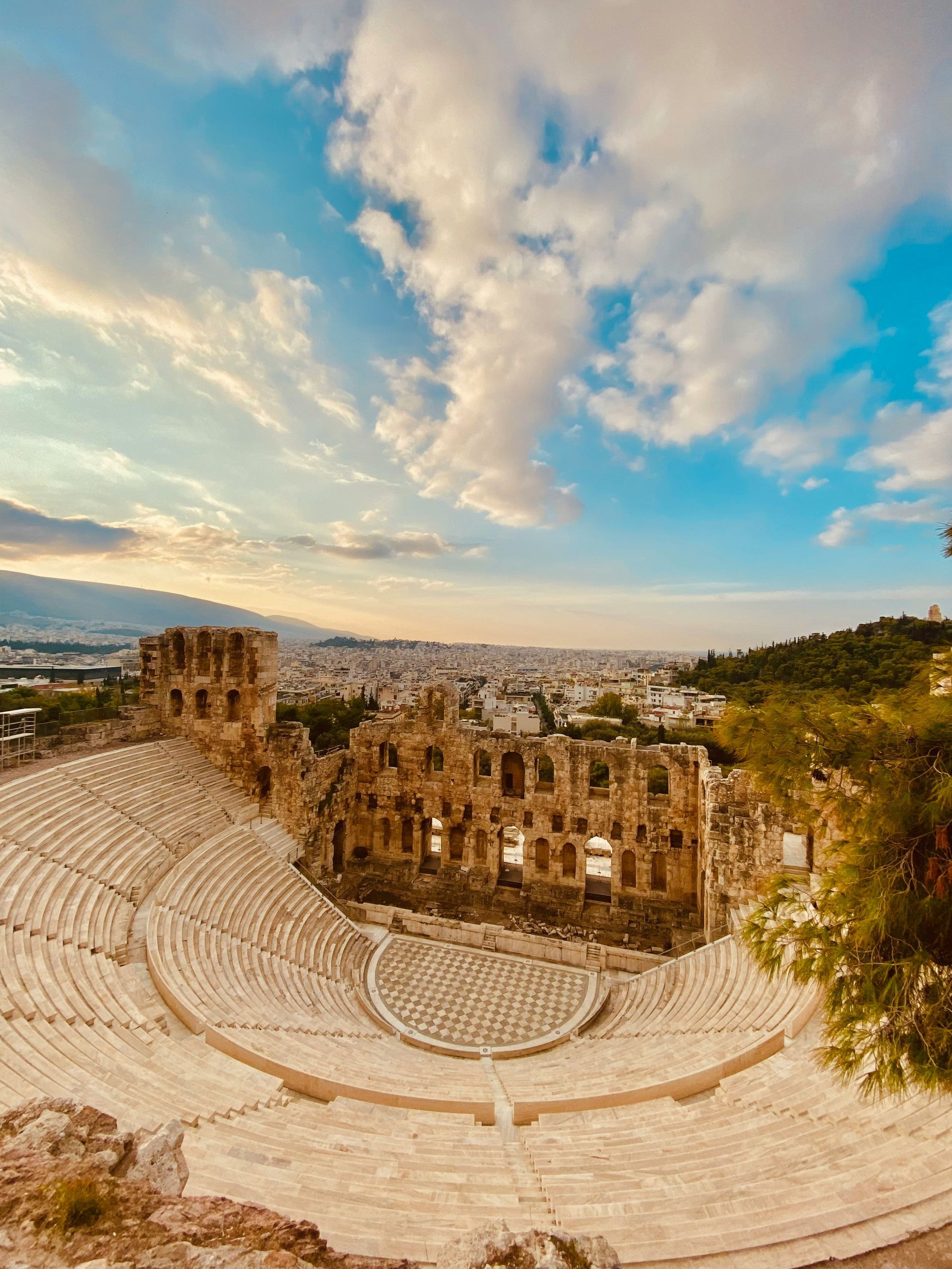 An aerial view of the Odeon of Herodes Atticus amphitheater with Athens, Greece in the background.