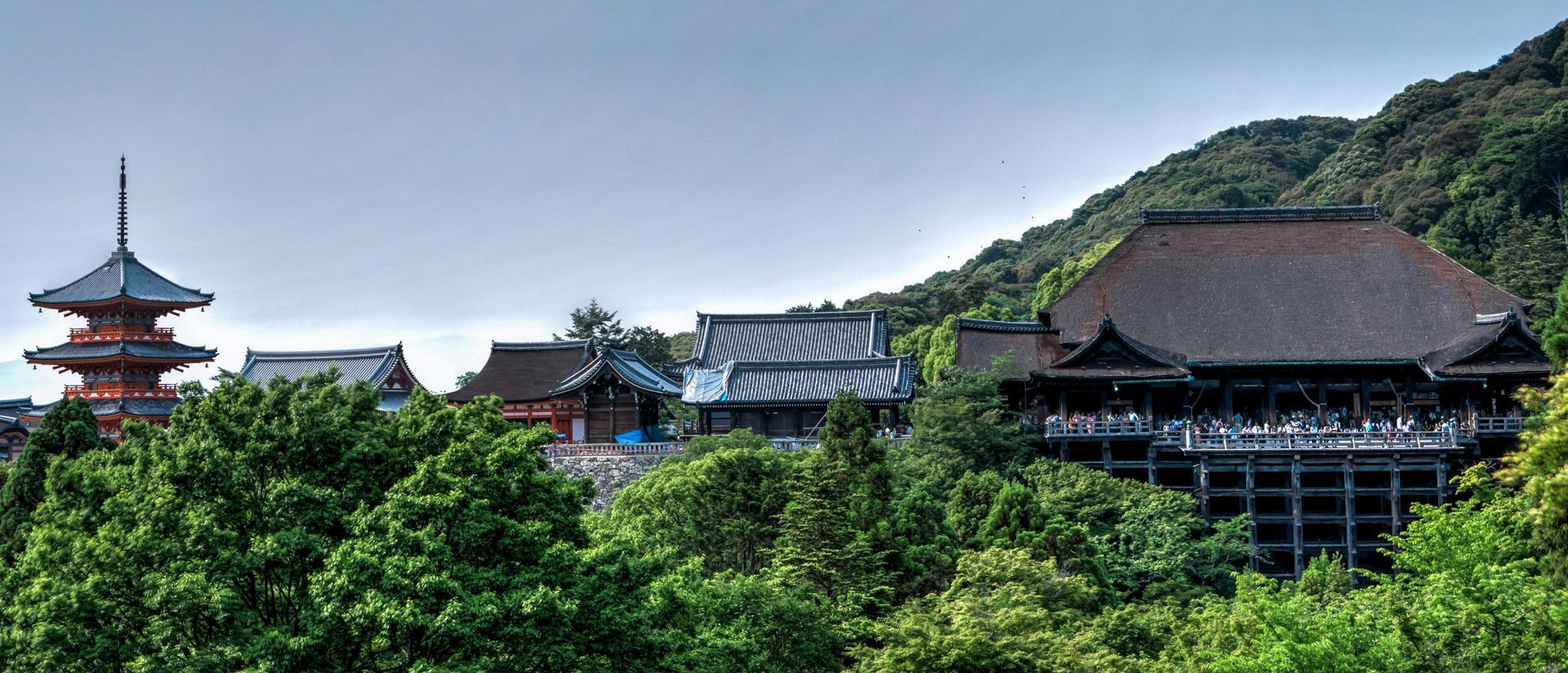 A large building is surrounded by trees and mountains in Japan.