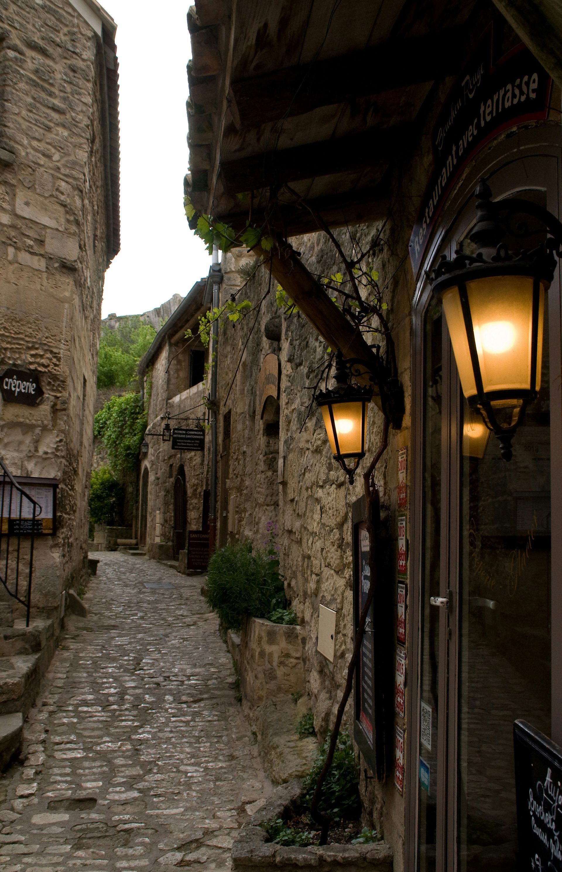 A narrow alleyway between two buildings with a lantern on the side of the building in Provence, France.